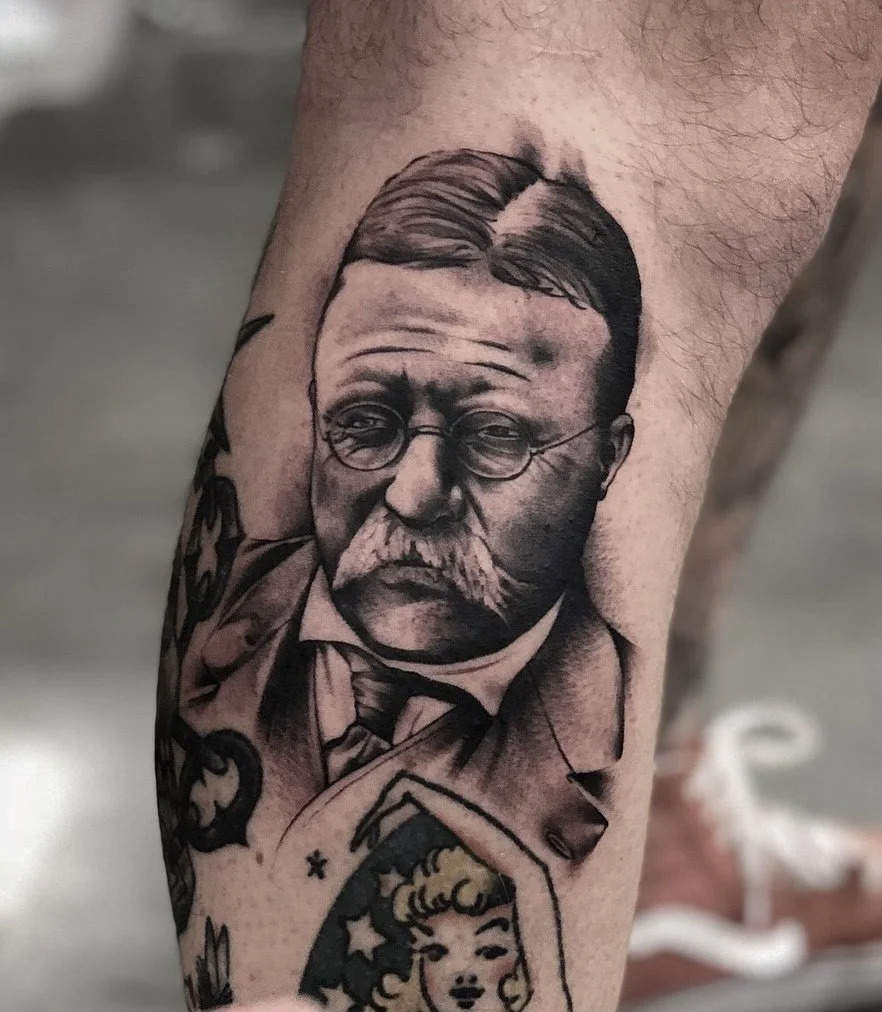 Black and grey Theodore Roosevelt portrait tattoo with fine lines and soft shading. Award-winning piece from 2018.