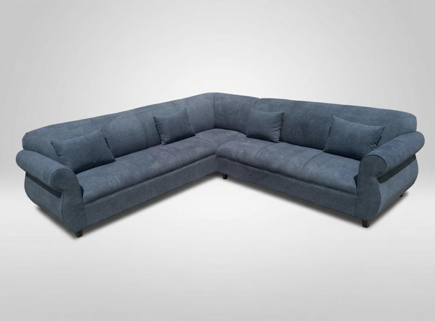 Blue L-shaped sectional sofa with five matching throw pillows on a plain white background.