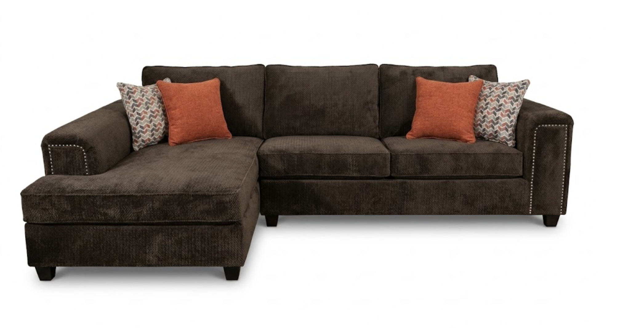 Dark brown sectional sofa with three decorative pillows, two orange and two with a multicolored chevron pattern, isolated on white background.