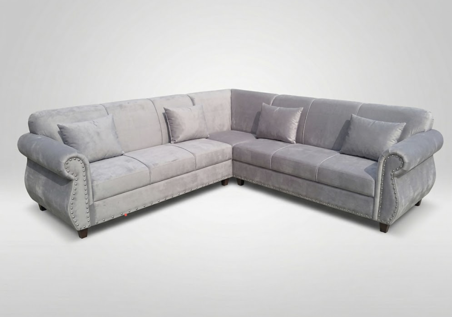 Gray sectional sofa with matching cushions and nailhead trim, set against a plain white background.