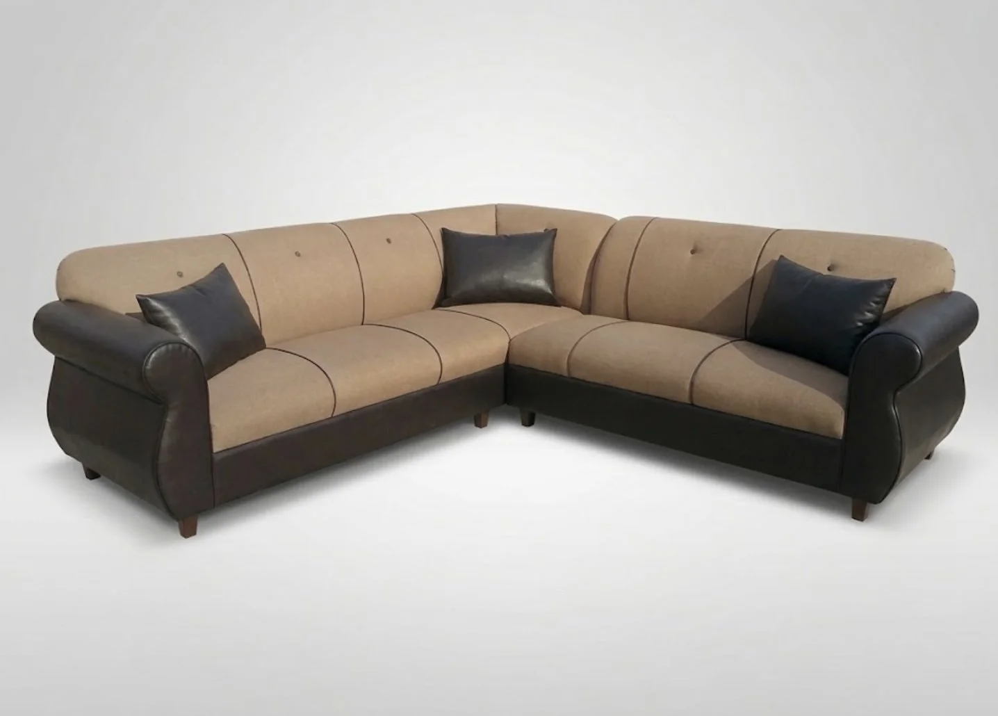 L-shaped sofa with beige upholstery, black leather armrests, and three black leather pillows on a white background.