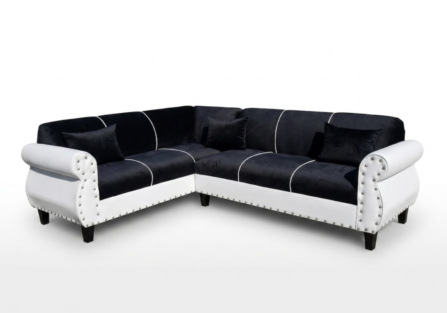 Black and white sectional sofa with black pillows against a white background.