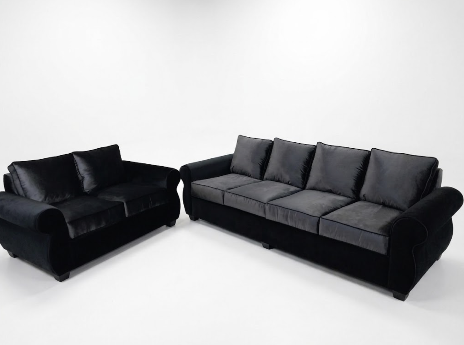 Two black sofas with velvet upholstery in a minimalist white room