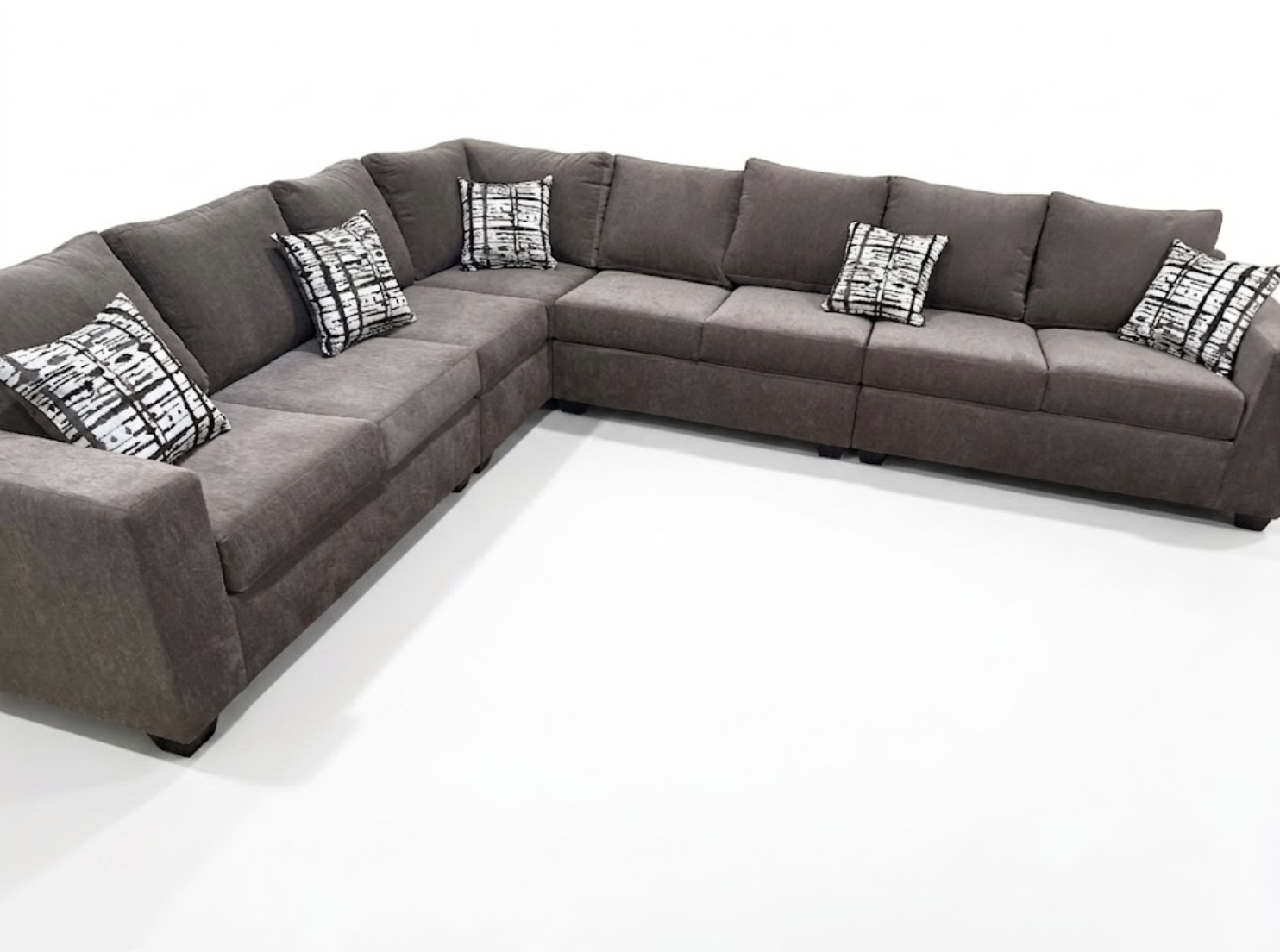 A large, L-shaped brown sectional sofa with black and white patterned throw pillows on a plain white background.