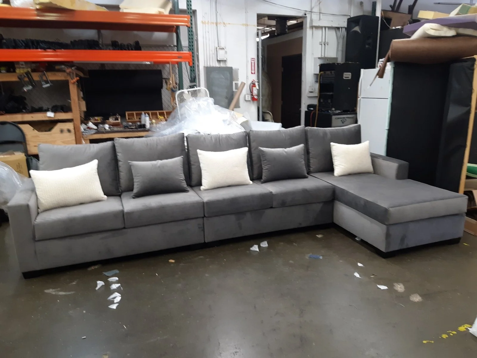 Gray sectional sofa with six cushions in a warehouse or storage unit.