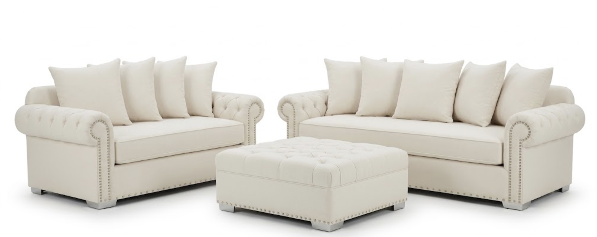 Two white upholstered sofas with matching cushions and a matching ottoman in the center, all with rolled arms and nailhead trim, set against a plain white background.