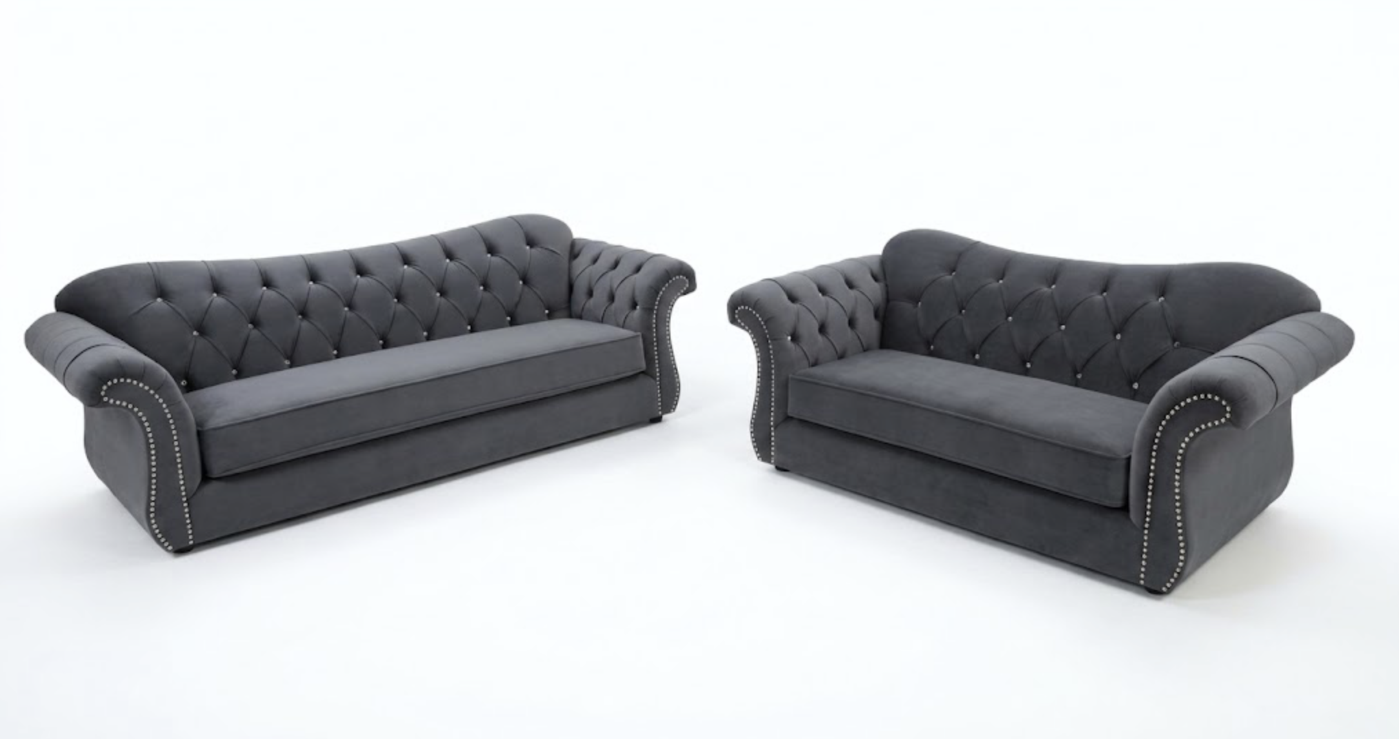 Two dark gray tufted sofas with rolled arms and nailhead trim, placed facing each other on a white background.