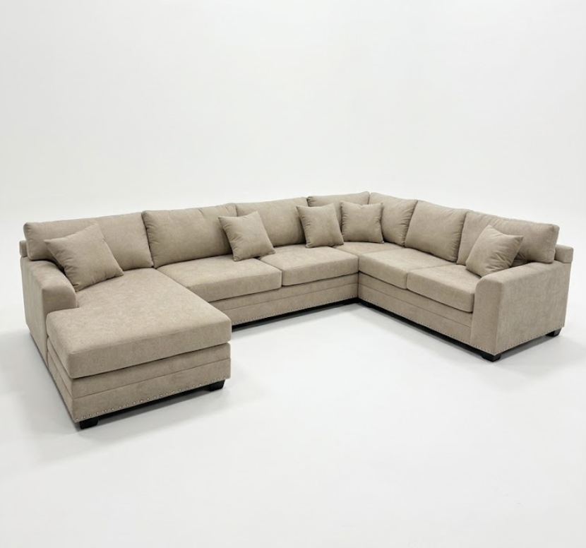 A beige L-shaped sectional sofa with matching pillows placed against a plain white wall.