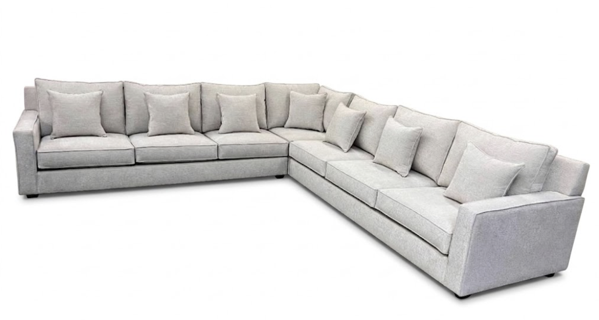 A large L-shaped light gray fabric sectional sofa with eight matching throw pillows, set against a plain white background.