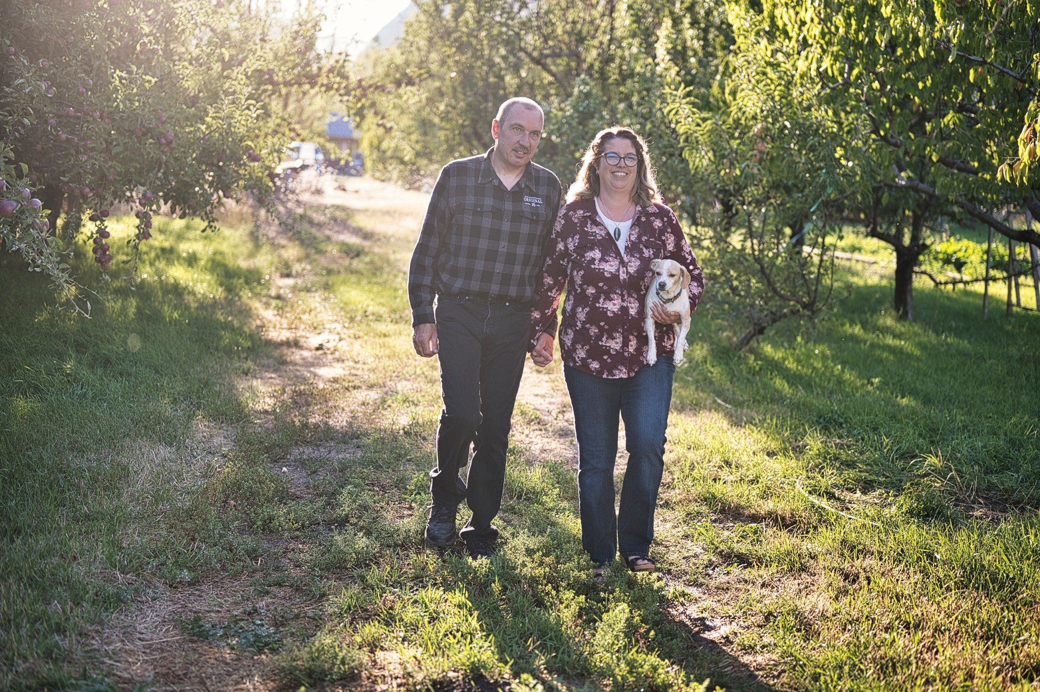 Donegal with her husband James and her dog Wilbur walking through an orchard on a sunny day.