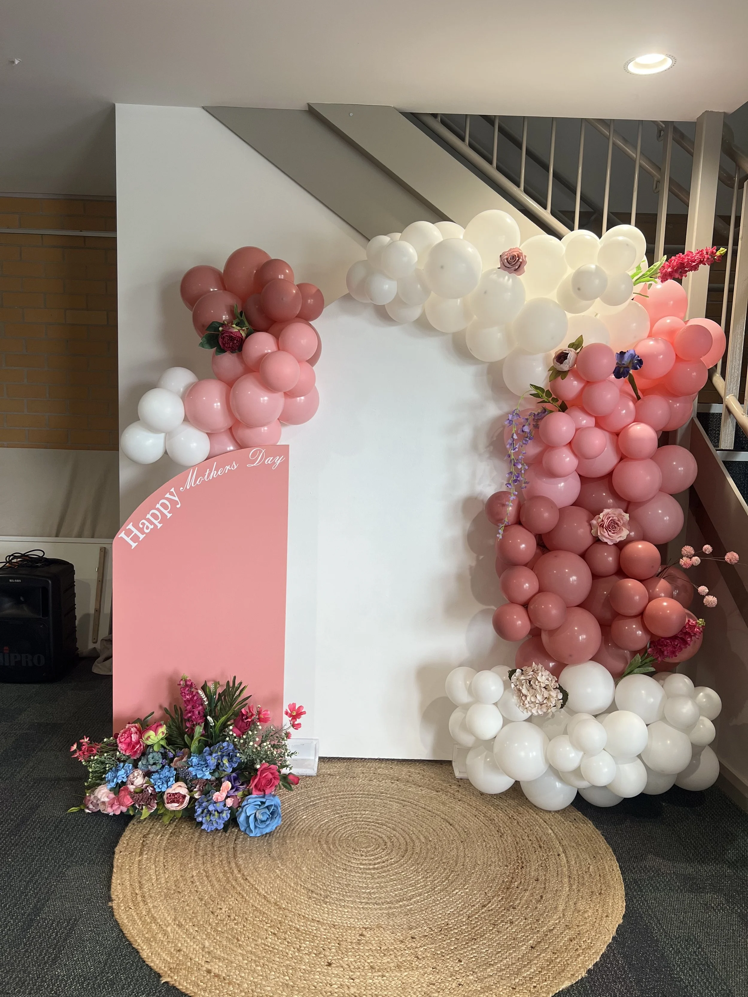 small pink sail and large white arch with jute rug, standard balloon garland, white custom vinyl and florals .jpg