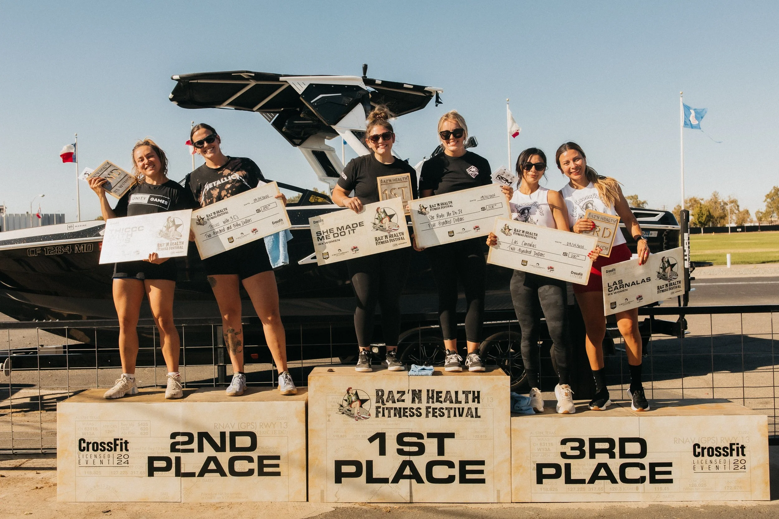 The women's RX division standing and smiling on the podium.