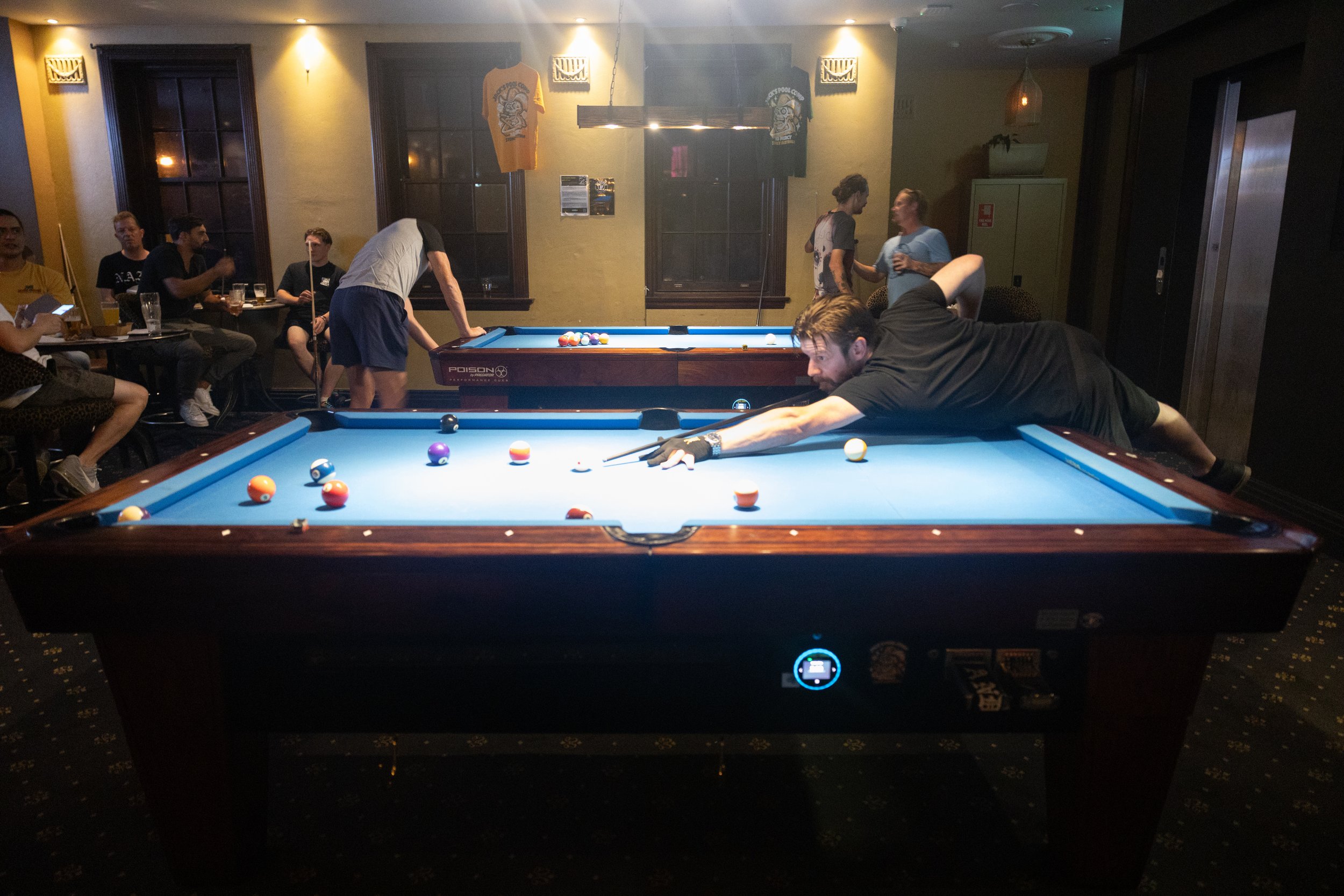 A man taking a pool shot in a bar with others watching