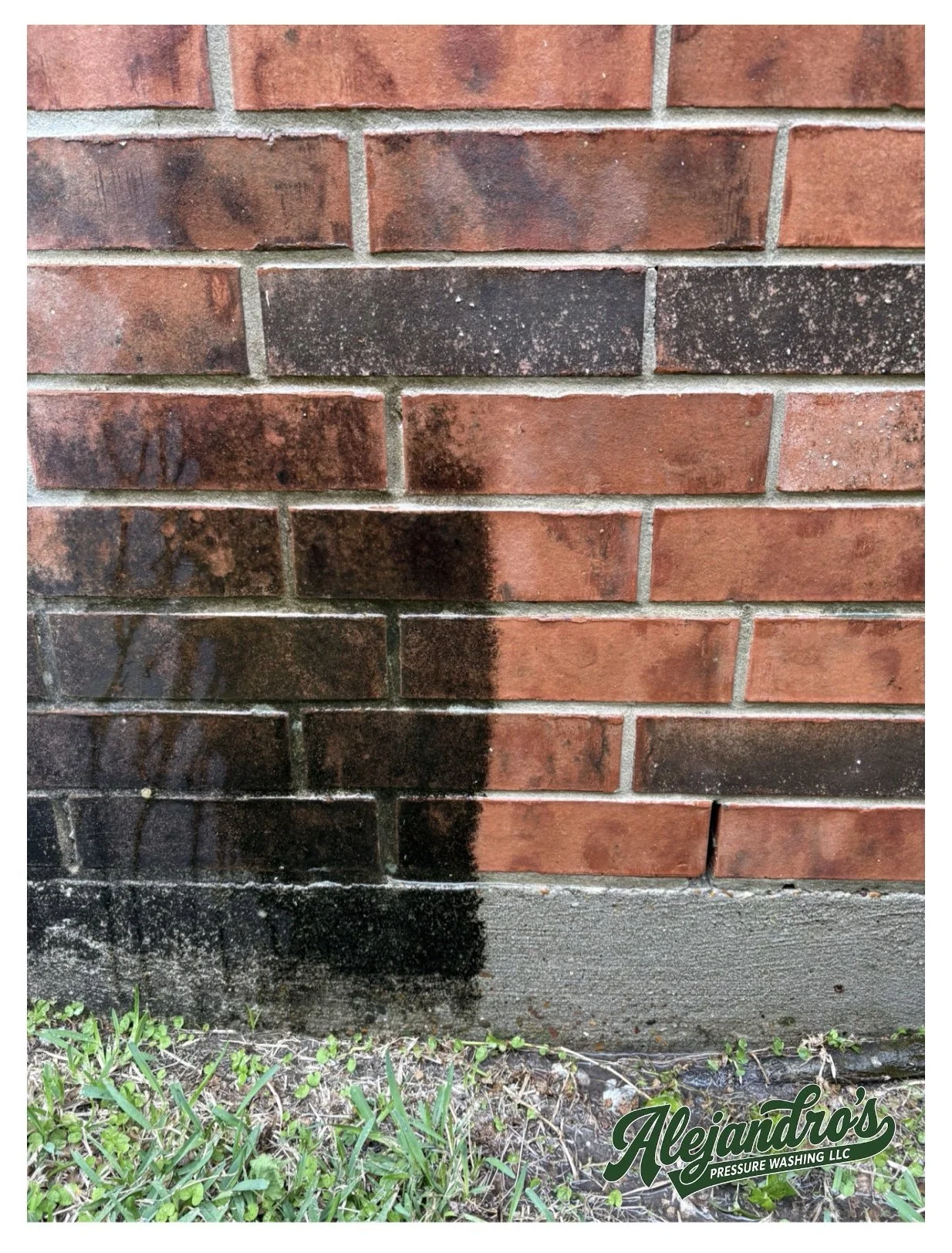 A brick wall with black and dark brown stains and mildew at the bottom, adjacent to green grass and a gray concrete sidewalk. A logo for 'Alejandro's Pressure Washing LLC' is at the bottom right corner.