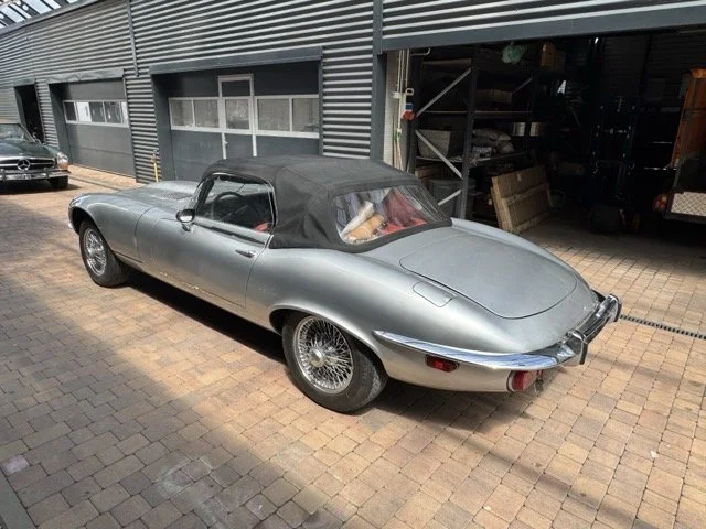 Silberner Jaguar Etype S3 V12 mit schwarzem Softtop im Außenbereich