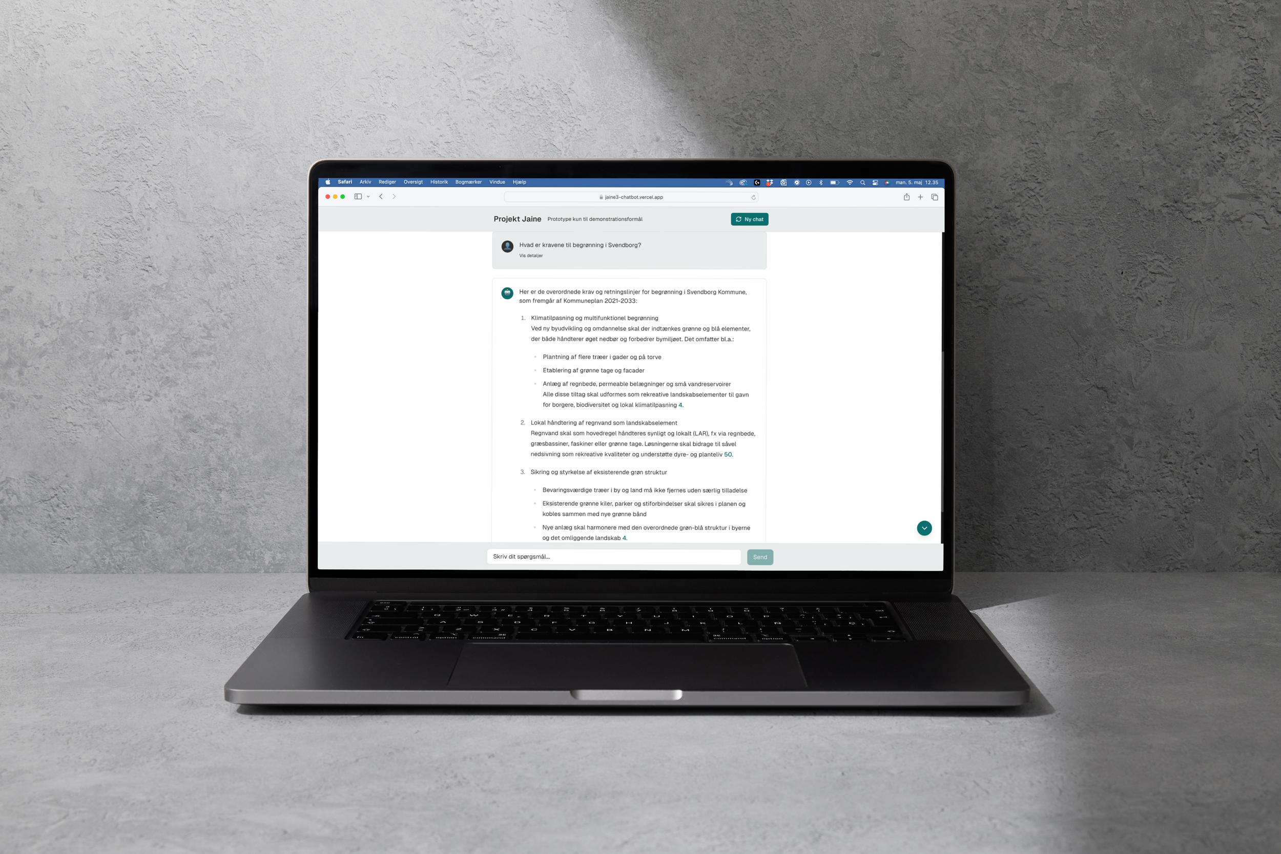 Open laptop on a gray surface displaying a text document on the screen, with a textured gray wall background.