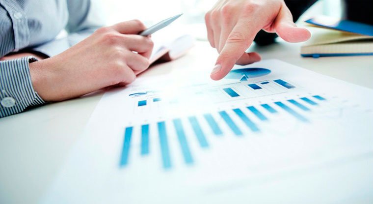 Two people discussing a financial report with bar graphs and diagrams on a desk.