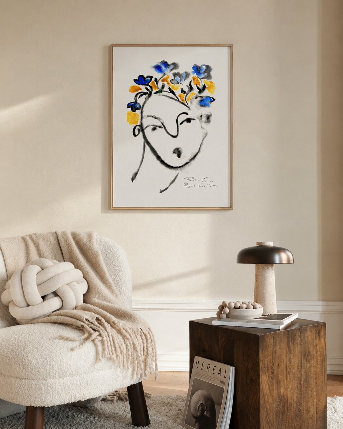 Framed print “August Boy” on a wall above a wooden side table and a soft throw blanket in a calm, neutral room