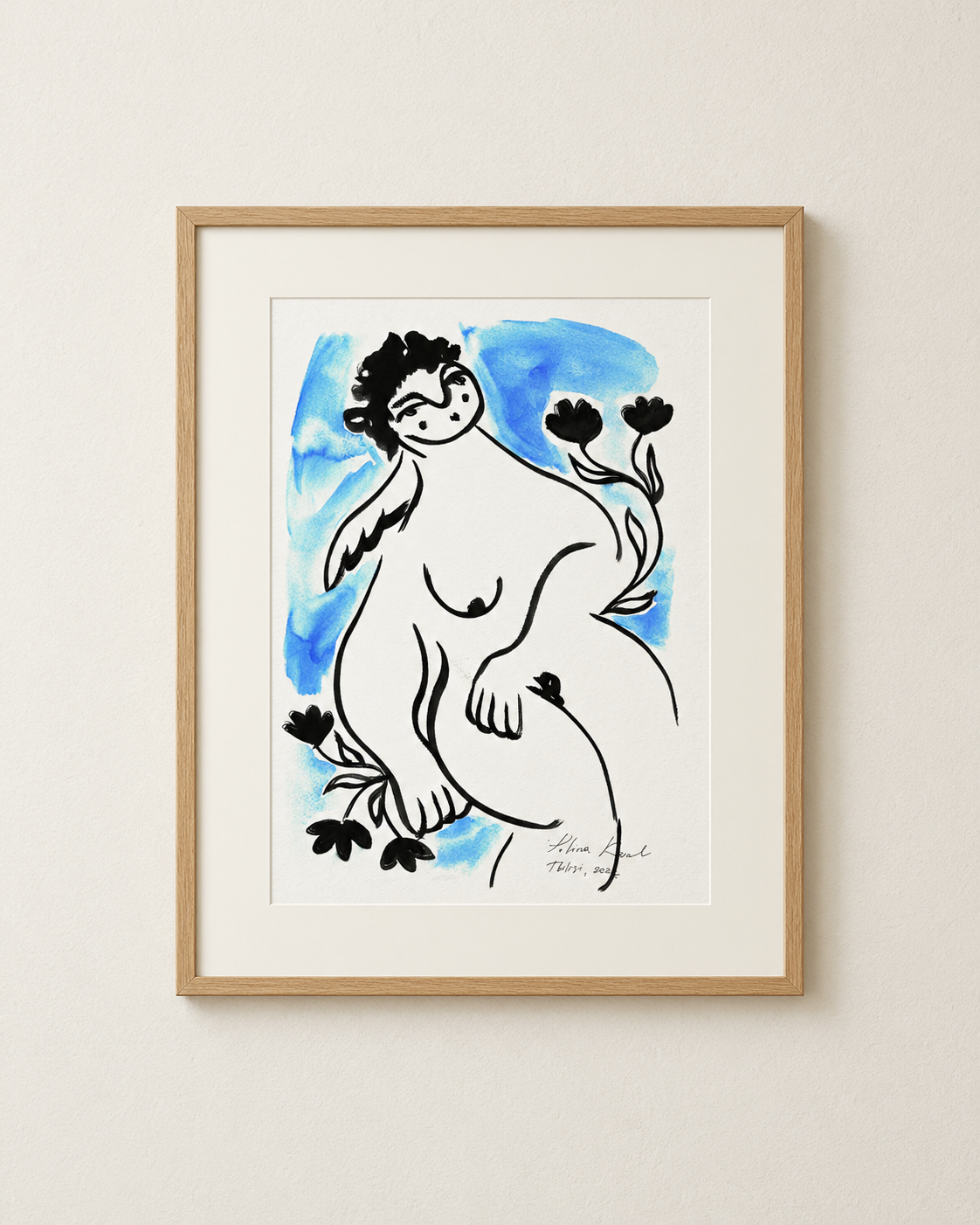 Angel by the Seaside framed print in a thin oak frame with a white mat on a plain cream wall.