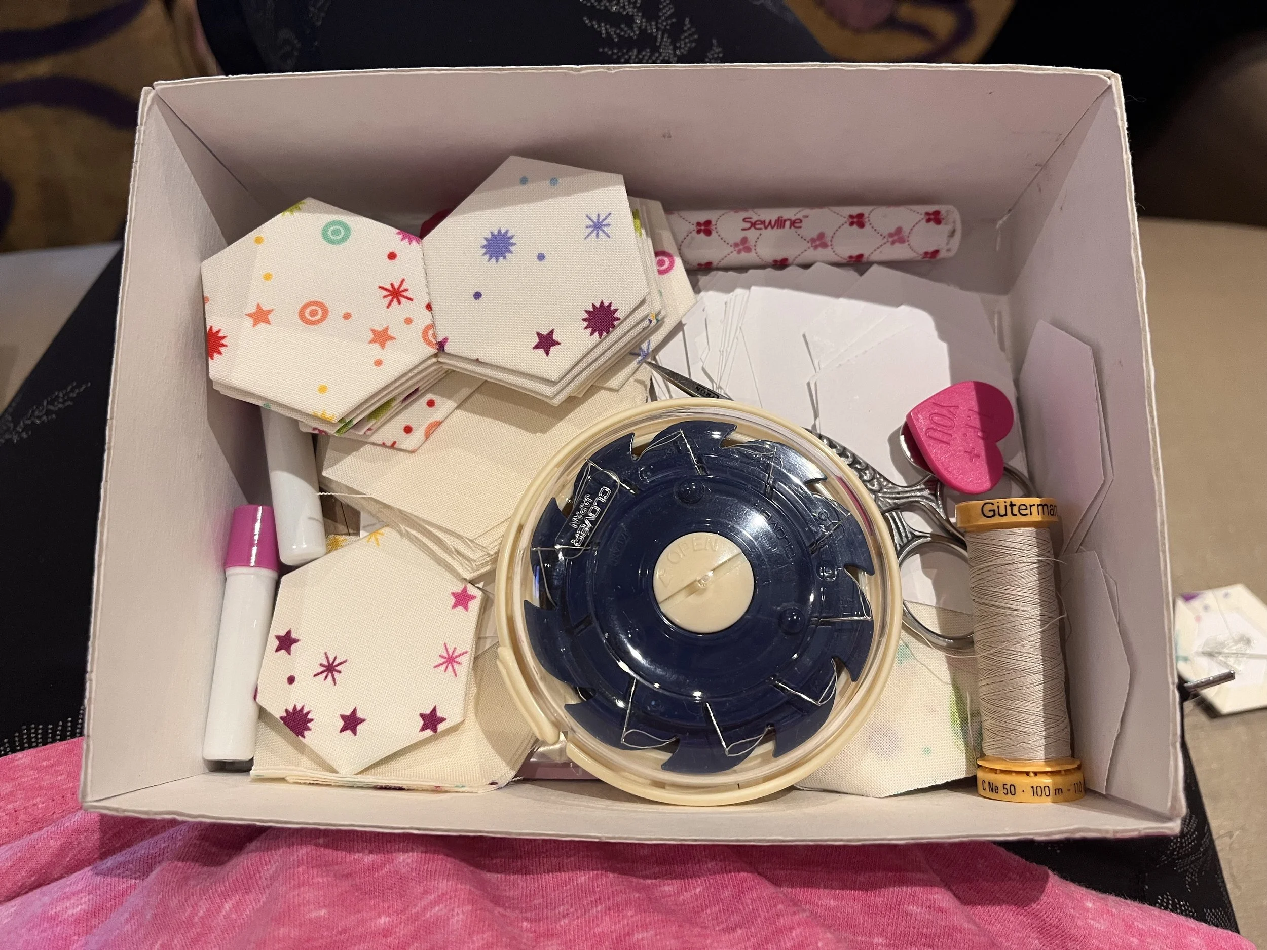 Photo of my sewing box contents. Pictured are basted hexagons, a Clover needle dome, Scissors, Thread, Sewtites Magnet and glue pen refills.