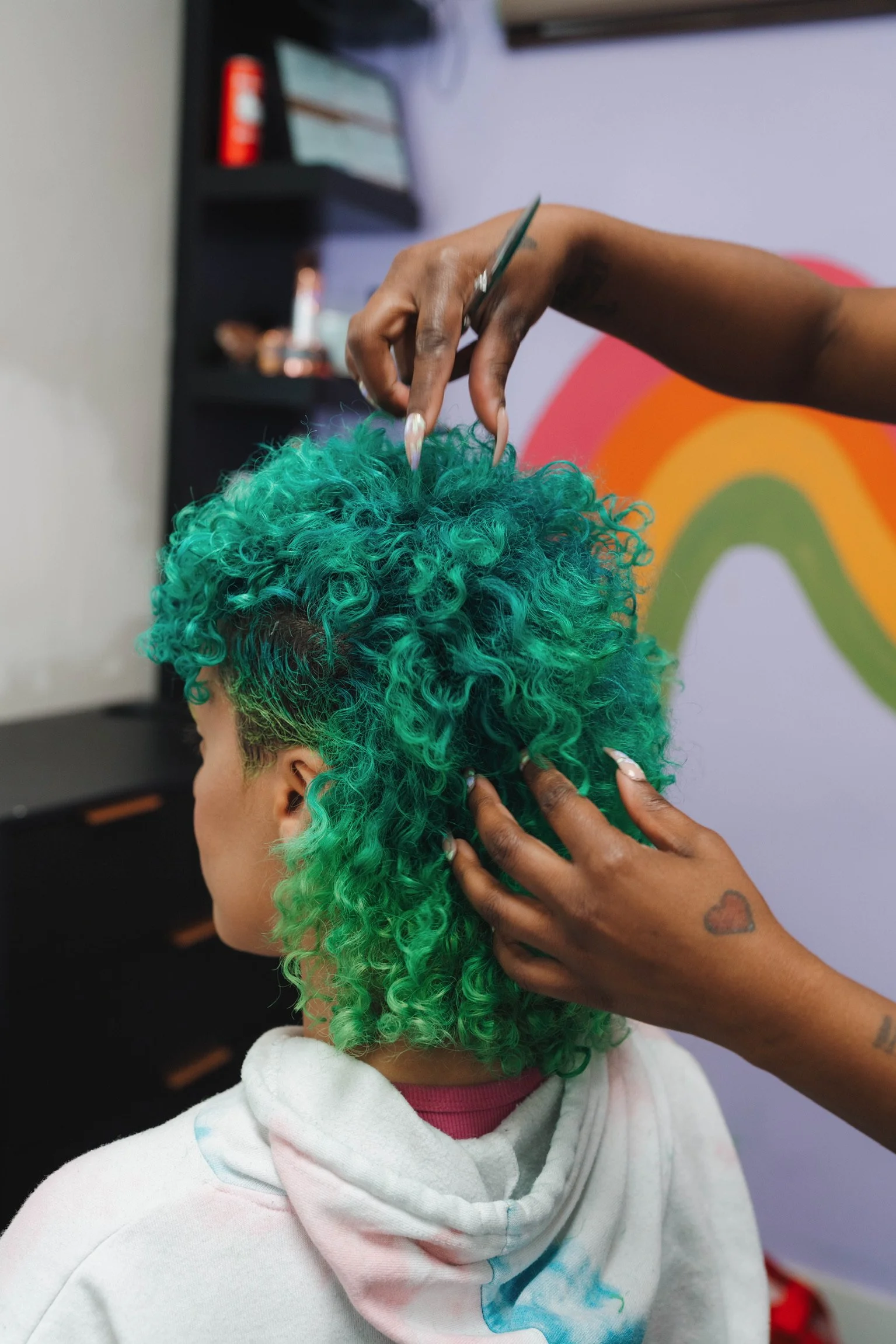 Stylist cutting vivid green curly hair at Alfa Jae Salon in Cary, NC