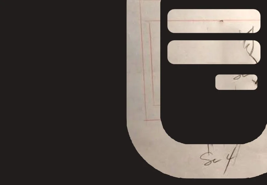Close-up of a black and white graphic design with a large black shape resembling a speech bubble or phone receiver, placed over a piece of paper with faint red lines and handwritten notes.