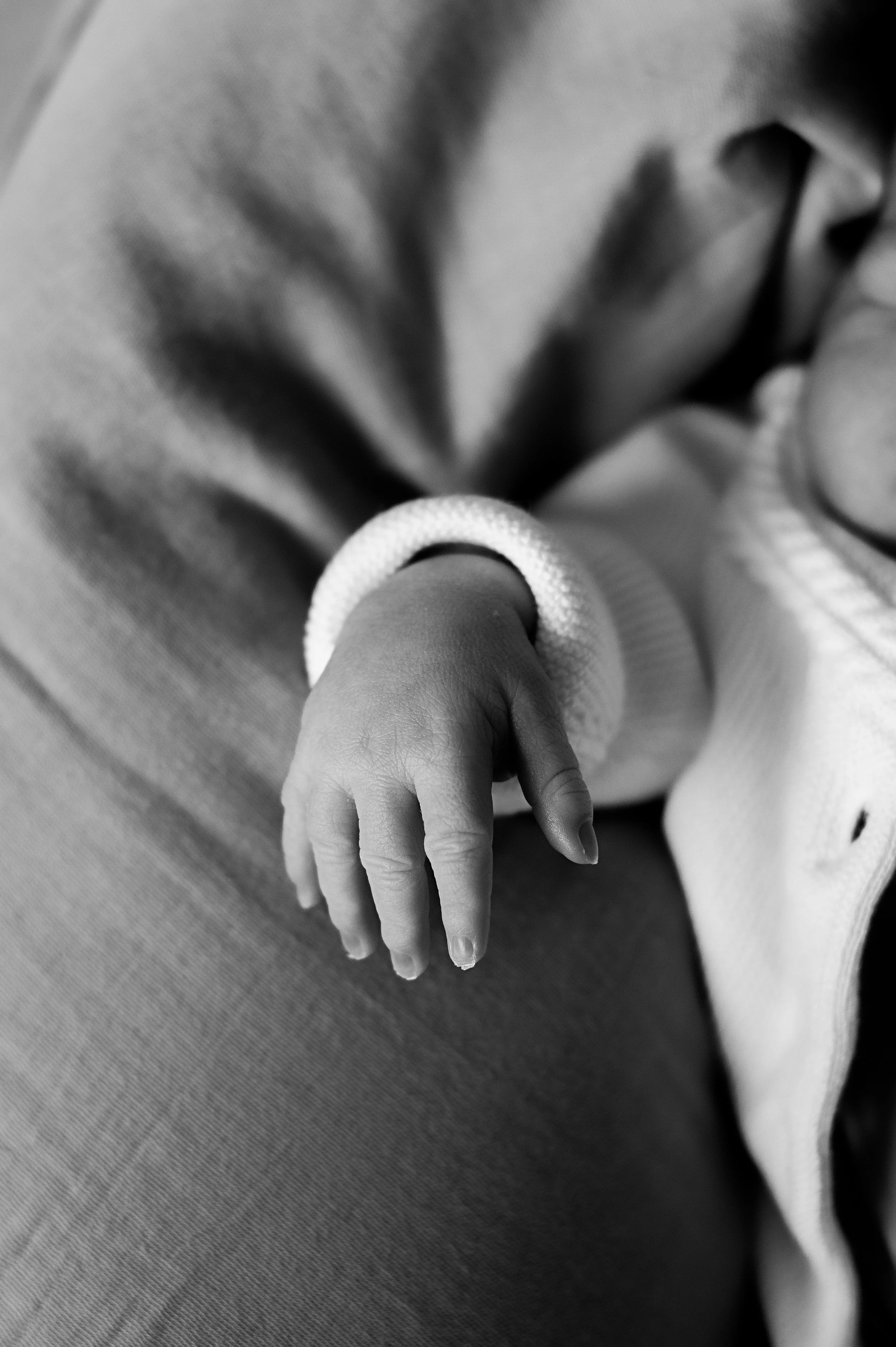 Main d'enfant posée sur une surface, en noir et blanc.