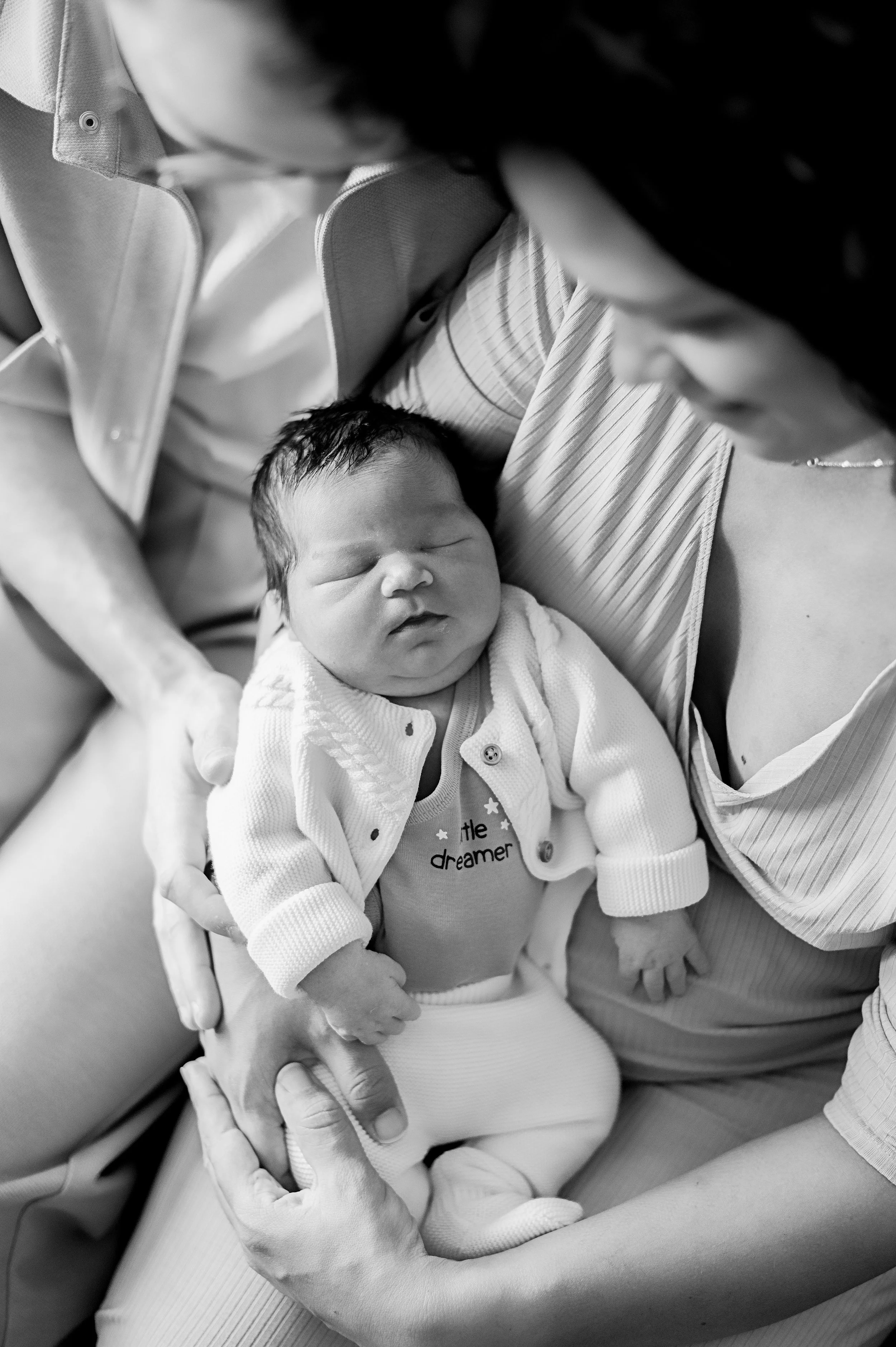 Une femme tient un bébé endormi dans ses bras, en noir et blanc.