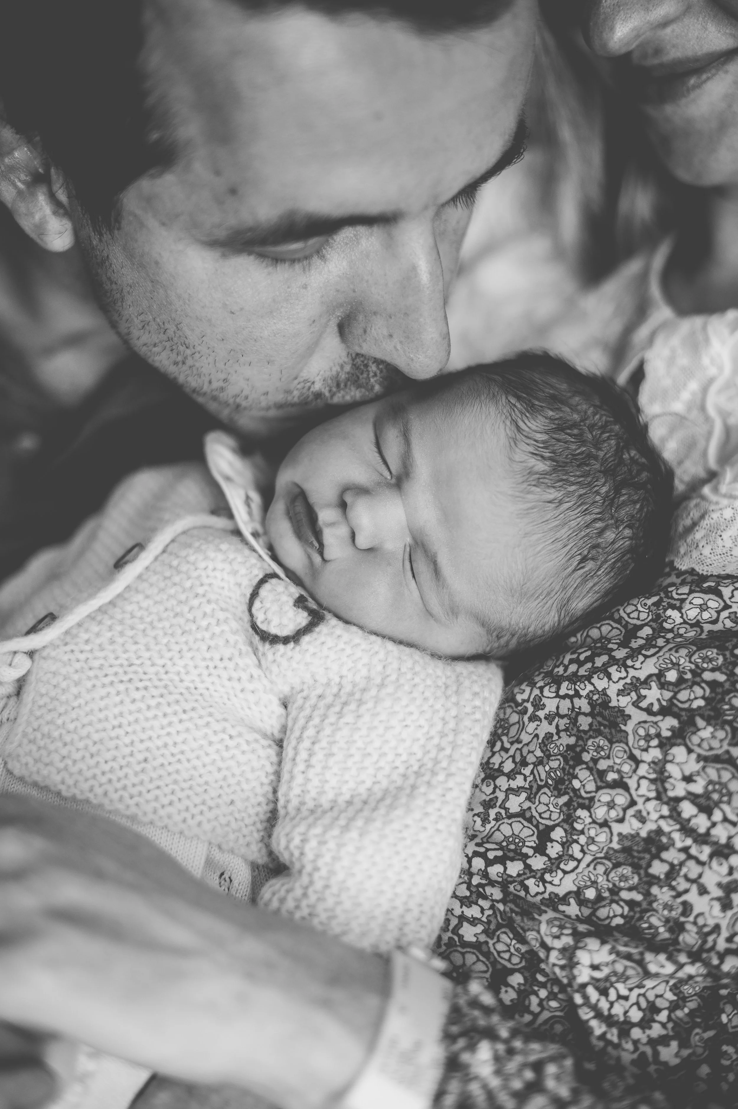 Un homme et une femme regardant tendrement un bébé endormi entre eux.