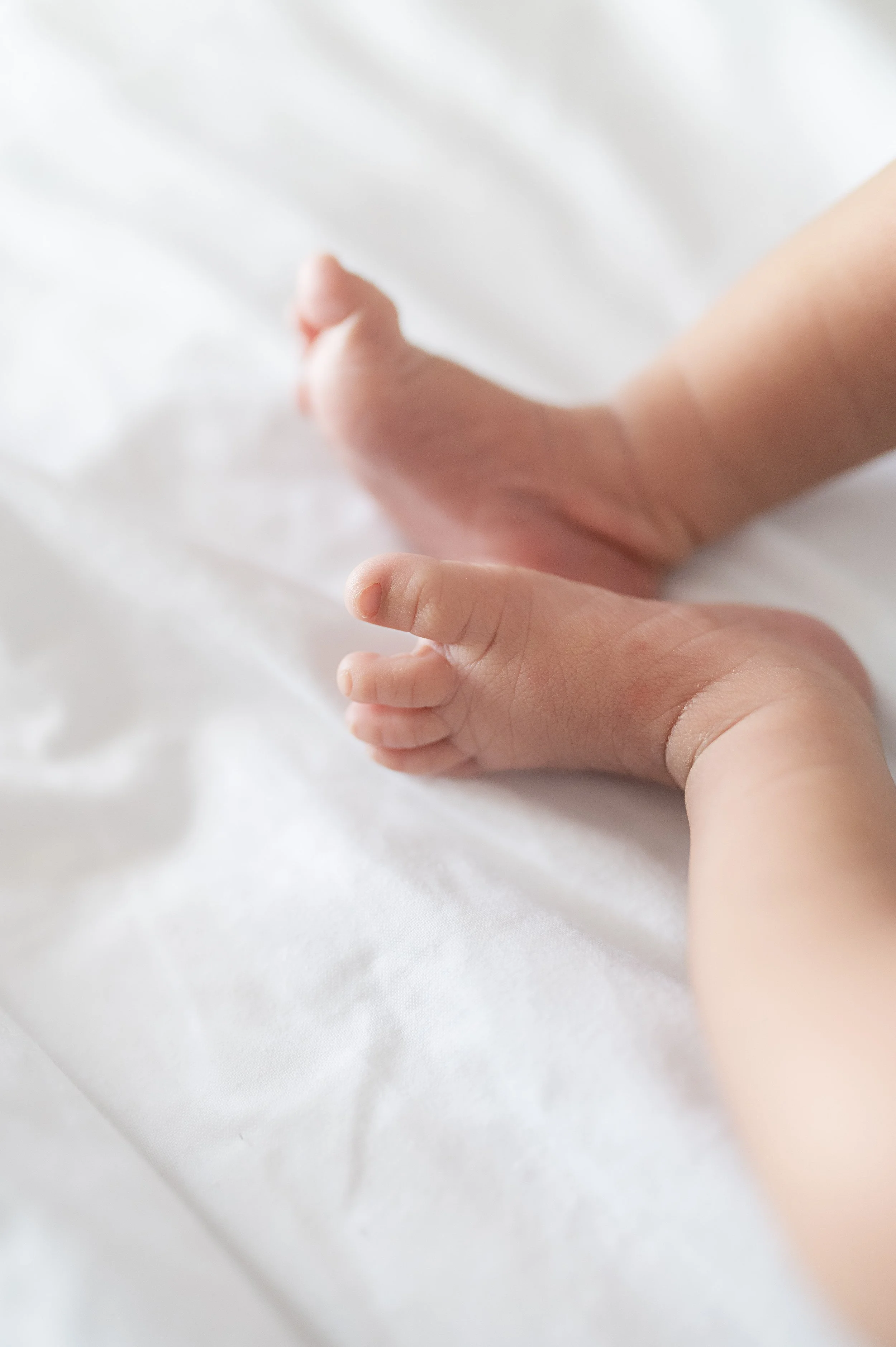 Mains de bébé posées sur une surface blanche.