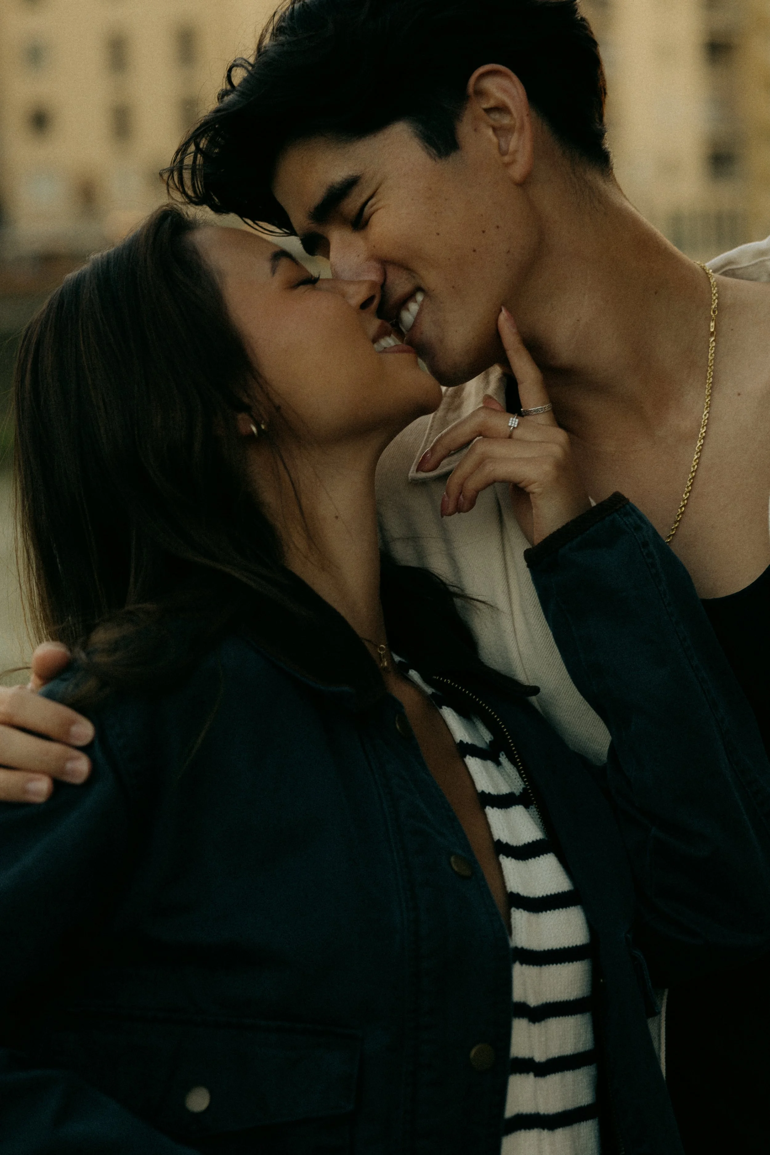 A man and woman share a close, intimate moment, touching noses and smiling.