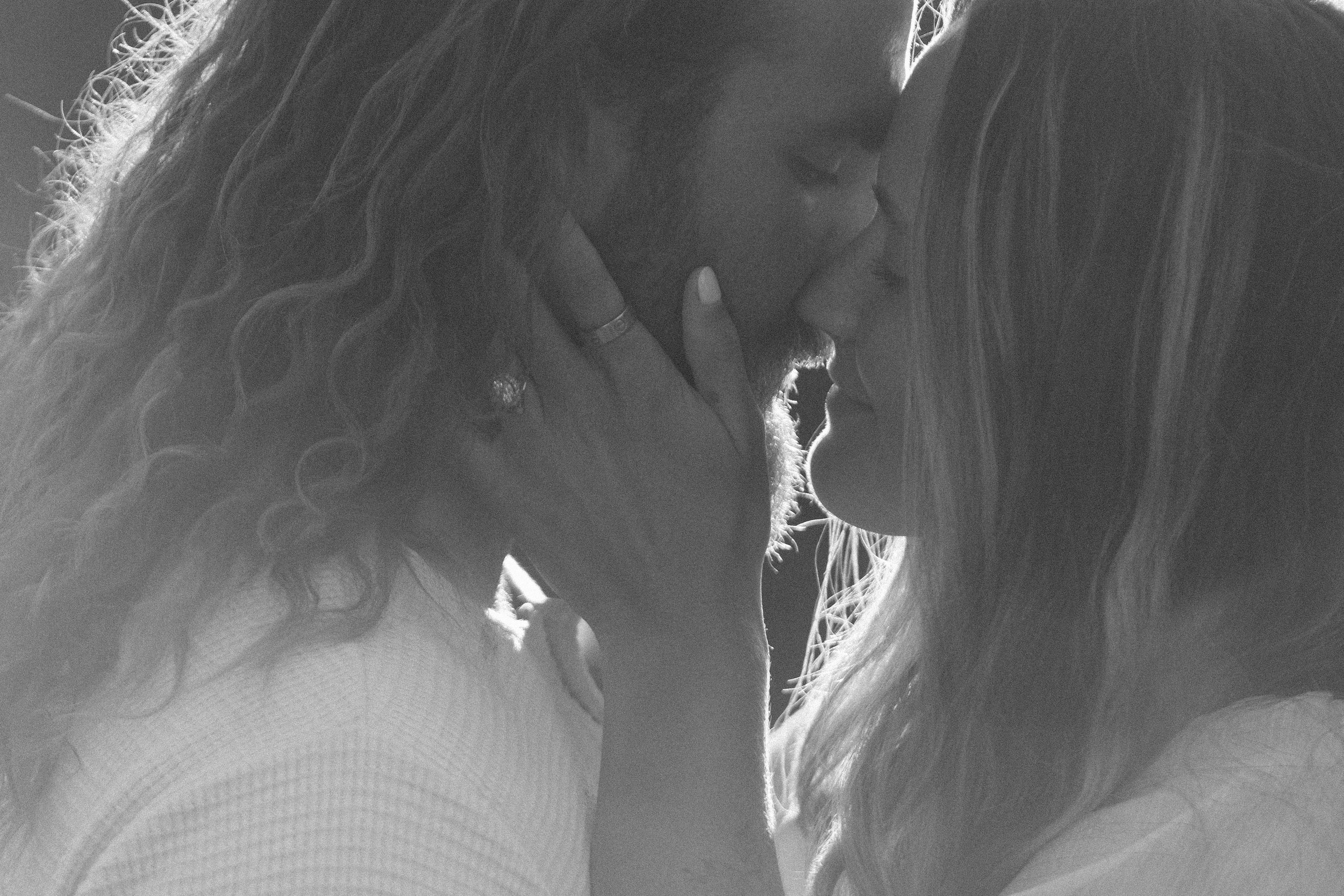 Two women sharing an intimate moment, touching foreheads, with one woman gently holding the other's face.