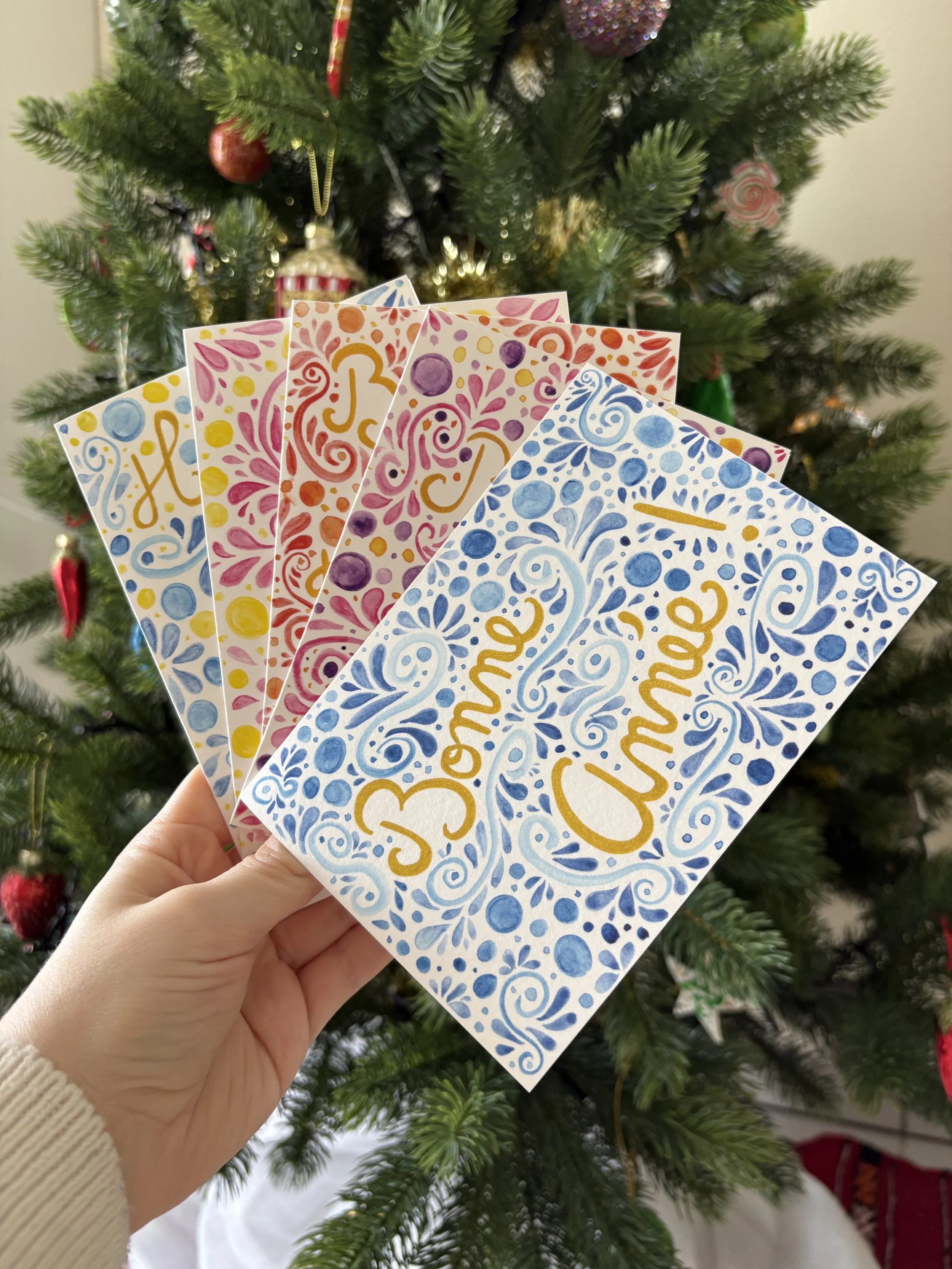 5 cartes artistiques de Mélila Victoria tenue devant un sapin de Noël