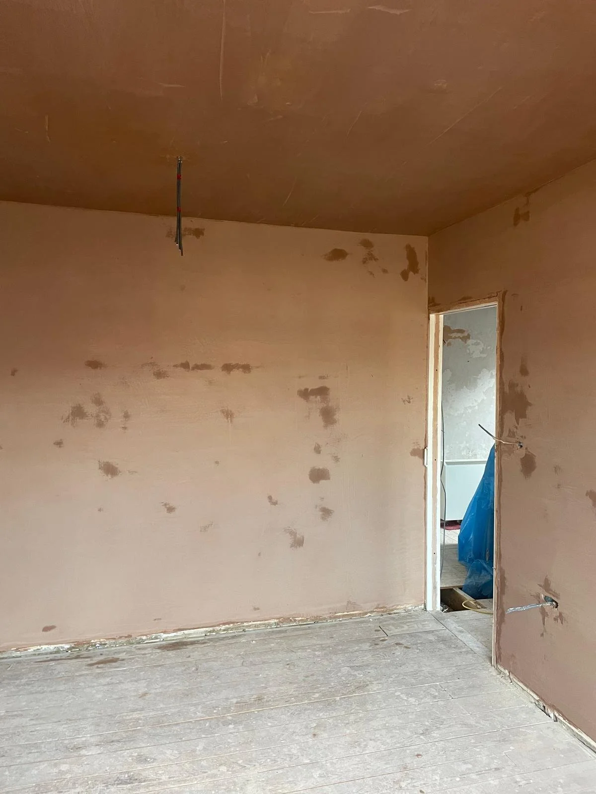 Interior of a room under construction with unfinished walls and visible electrical wiring.