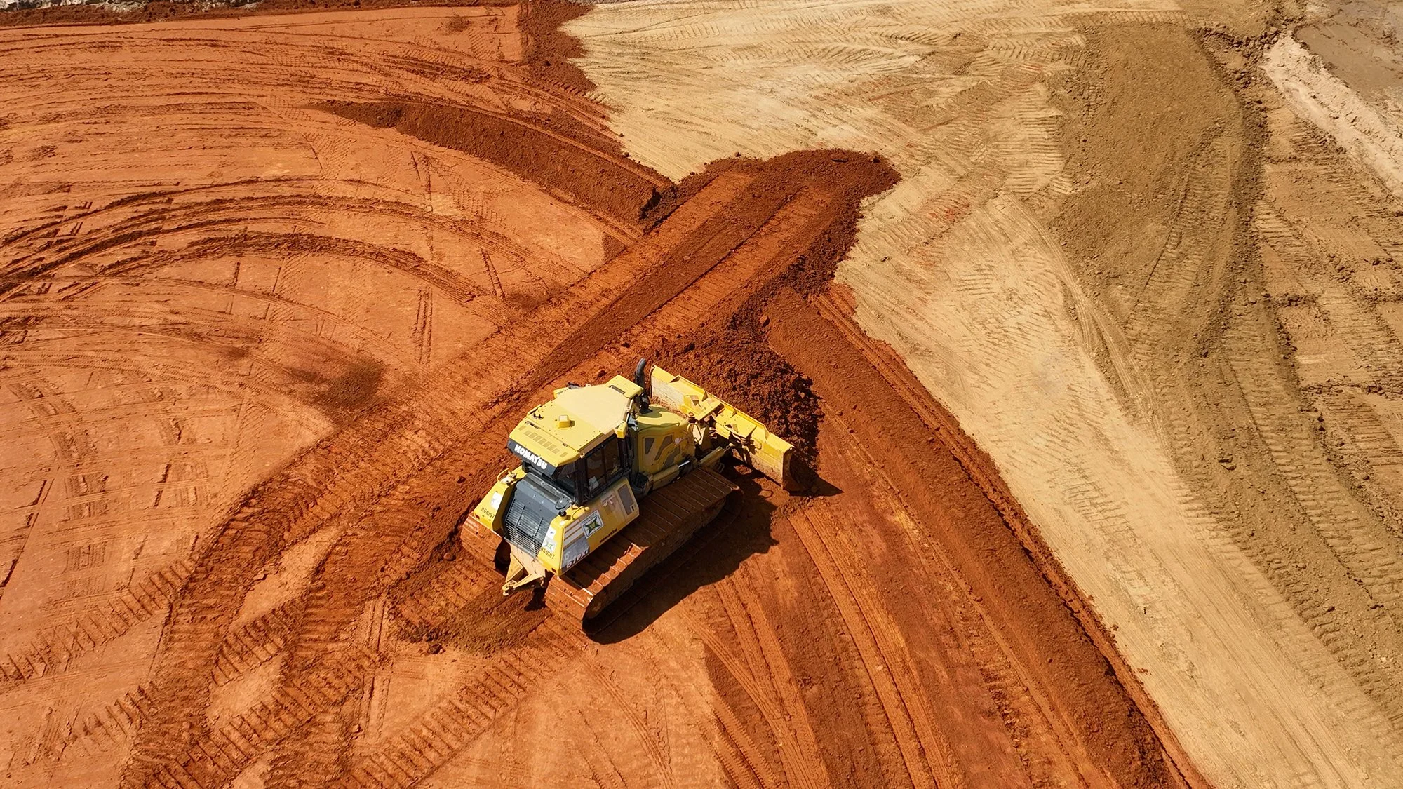 A bulldozer is engaged in work on a dirt road, transforming the terrain for future development and infrastructure.