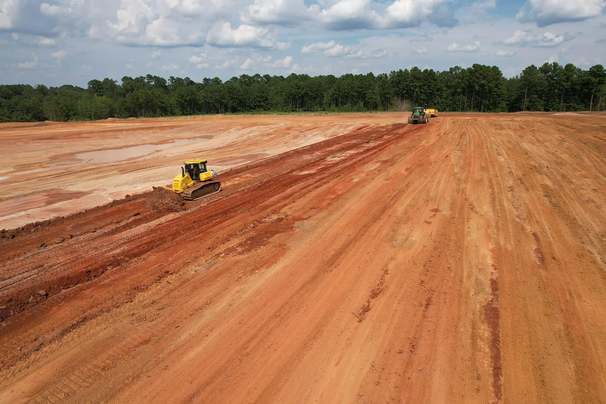 A bulldozer operates on a dirt road, clearing and leveling the ground for upcoming construction projects.