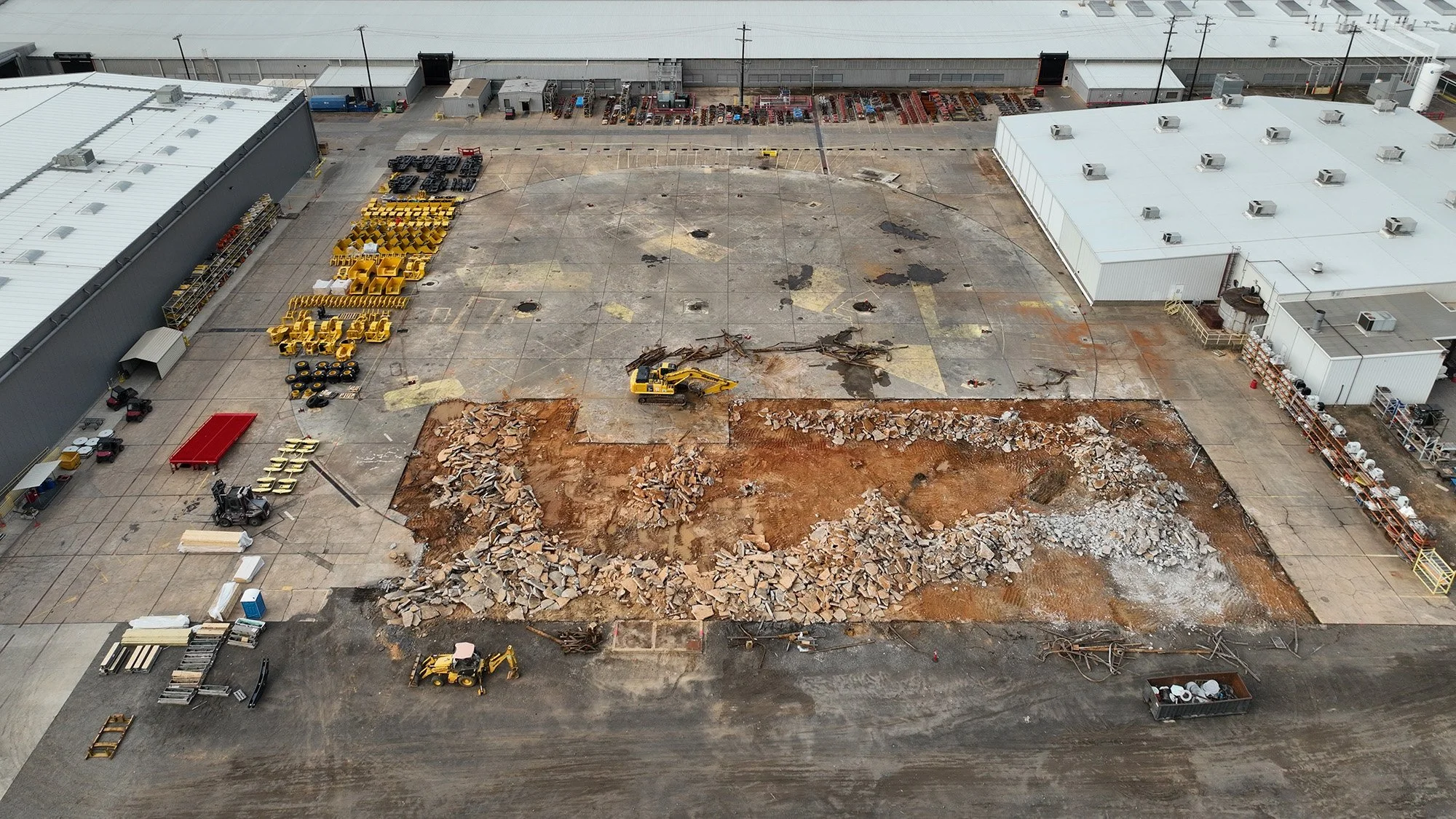 Overhead perspective of a construction site with a crane and heavy machinery actively working on the project.