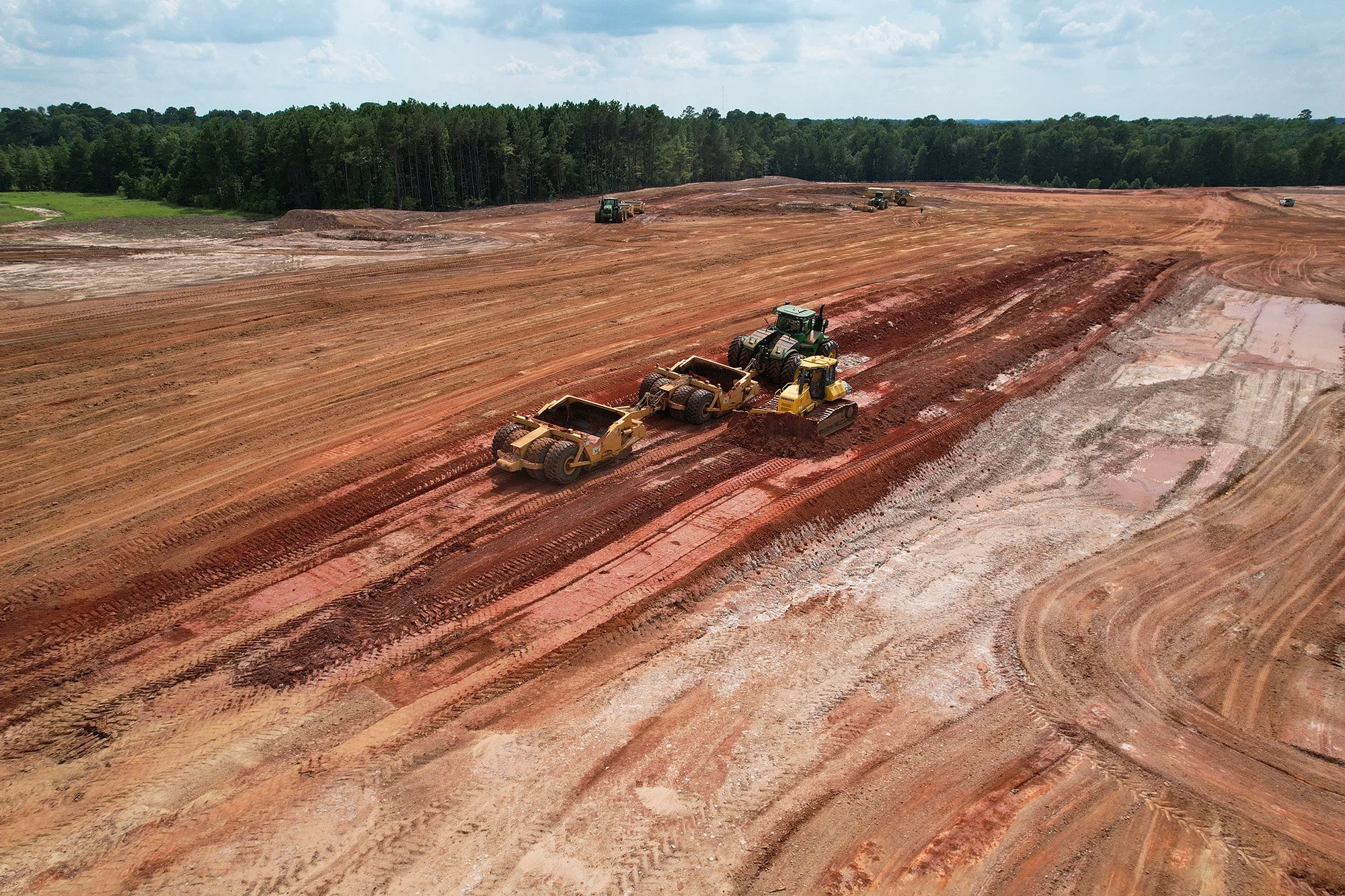 A bulldozer is actively working on a dirt field, reshaping the terrain for upcoming construction projects.