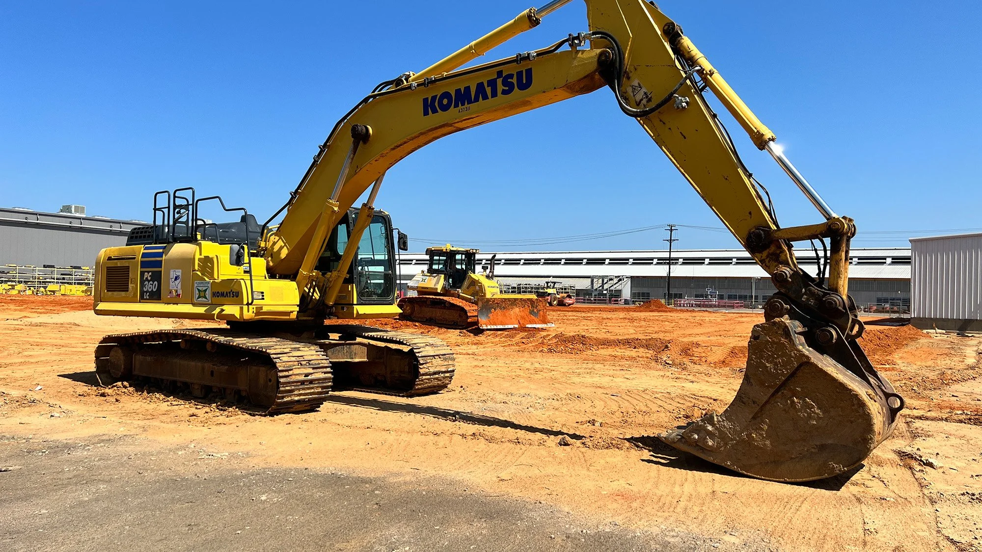 A yellow excavator positioned on a mound of dirt, ready for construction work.