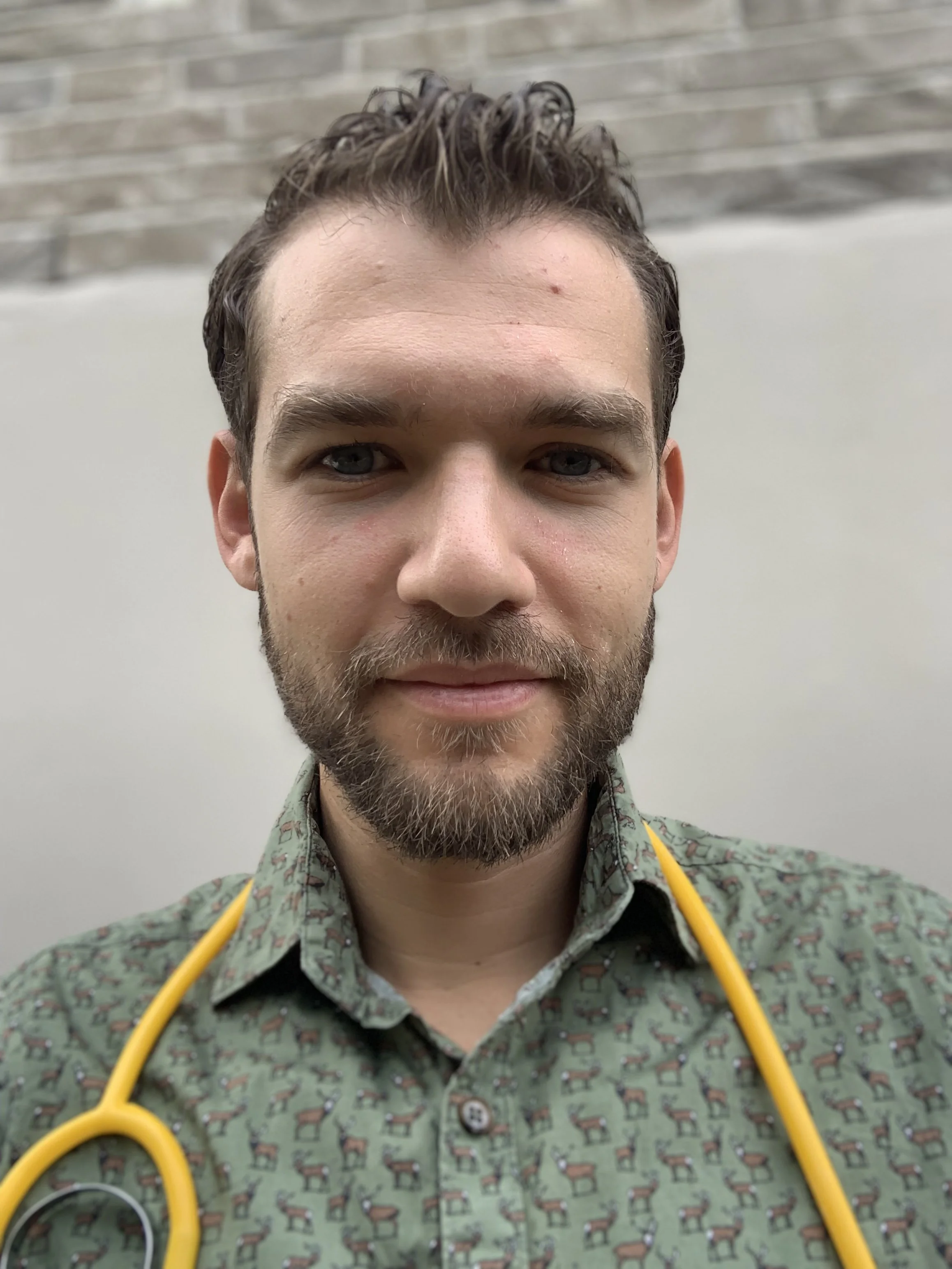 Man with a beard wearing a greenshirt and yellow stethoscope