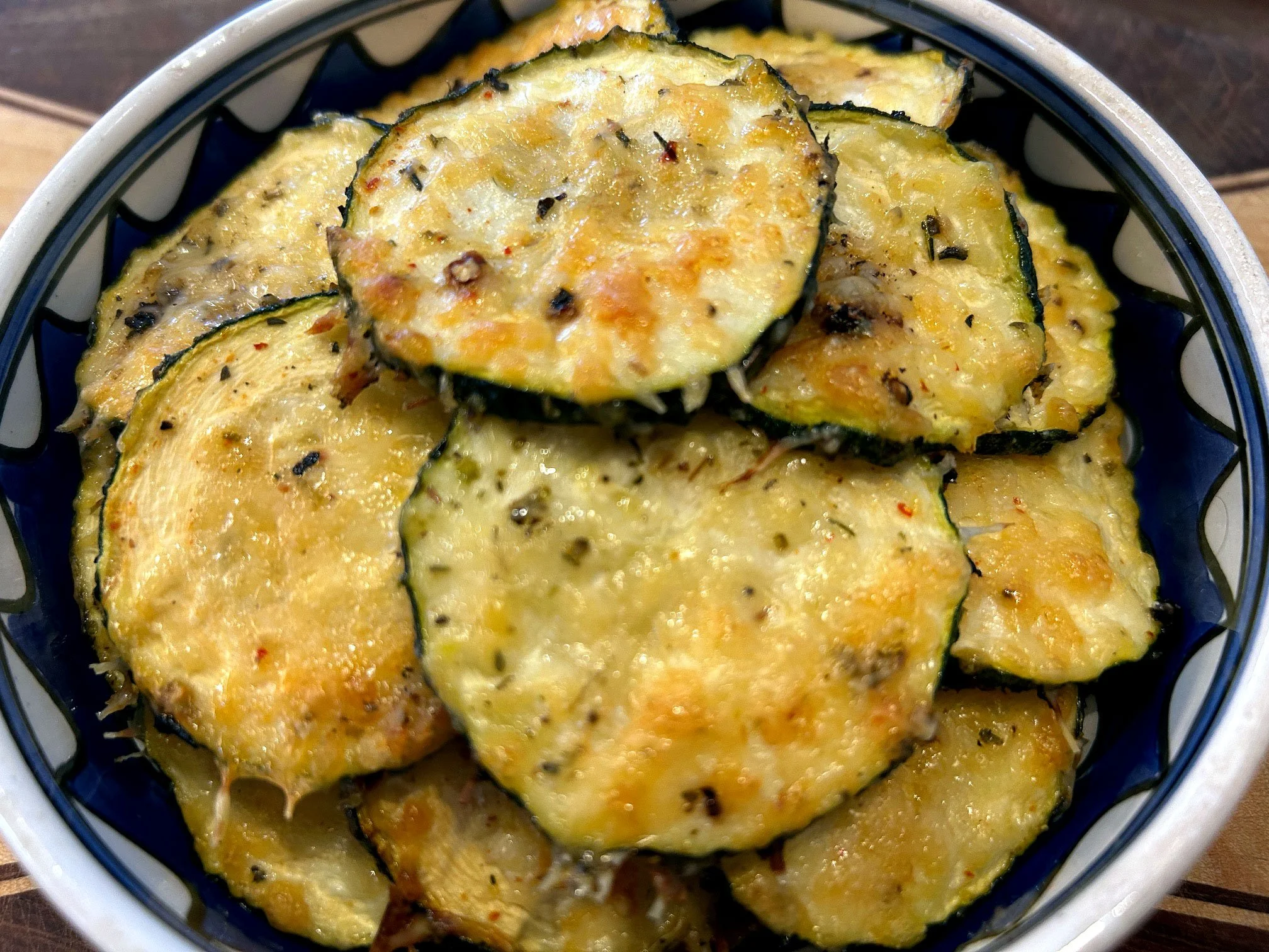 Zucchini slices coates with melted cheese and seasoning.
