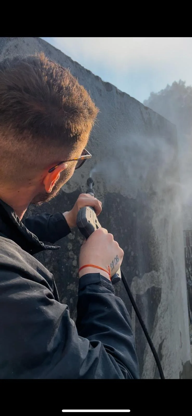 Un homme cherchant à percer une roche avec un équipement de forage dans une zone rocheuse en plein jour.