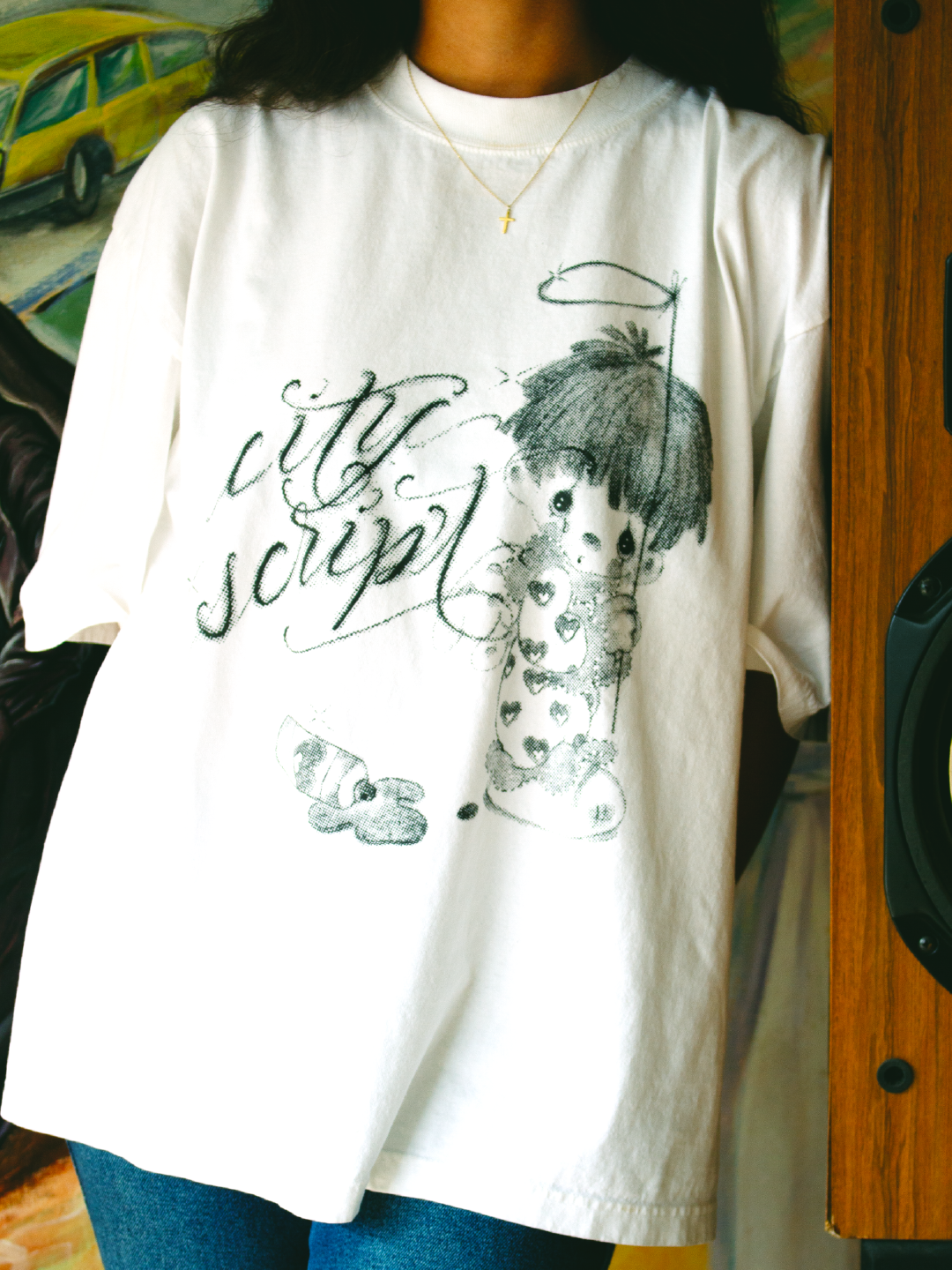 Zoom in of precious moments design of kid holding a halo with the words city script next to him