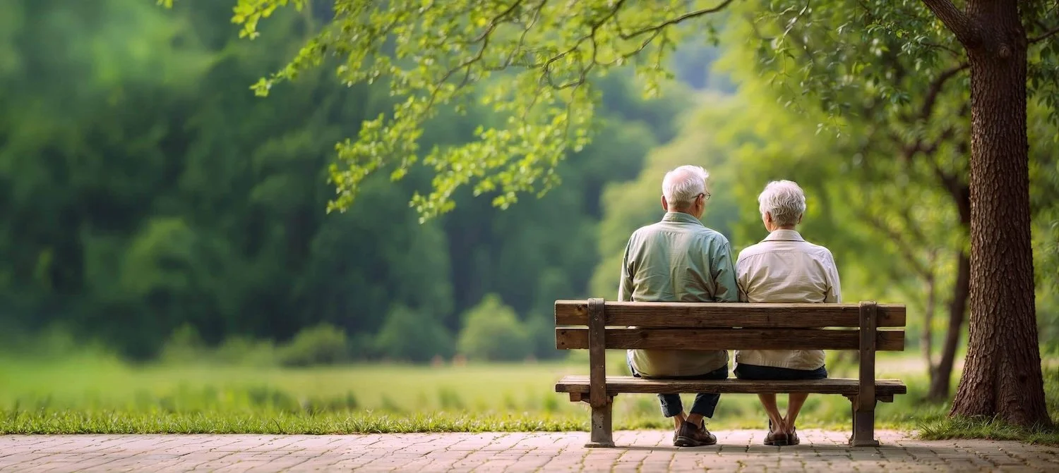 Two people sitting together on a park bench under the trees