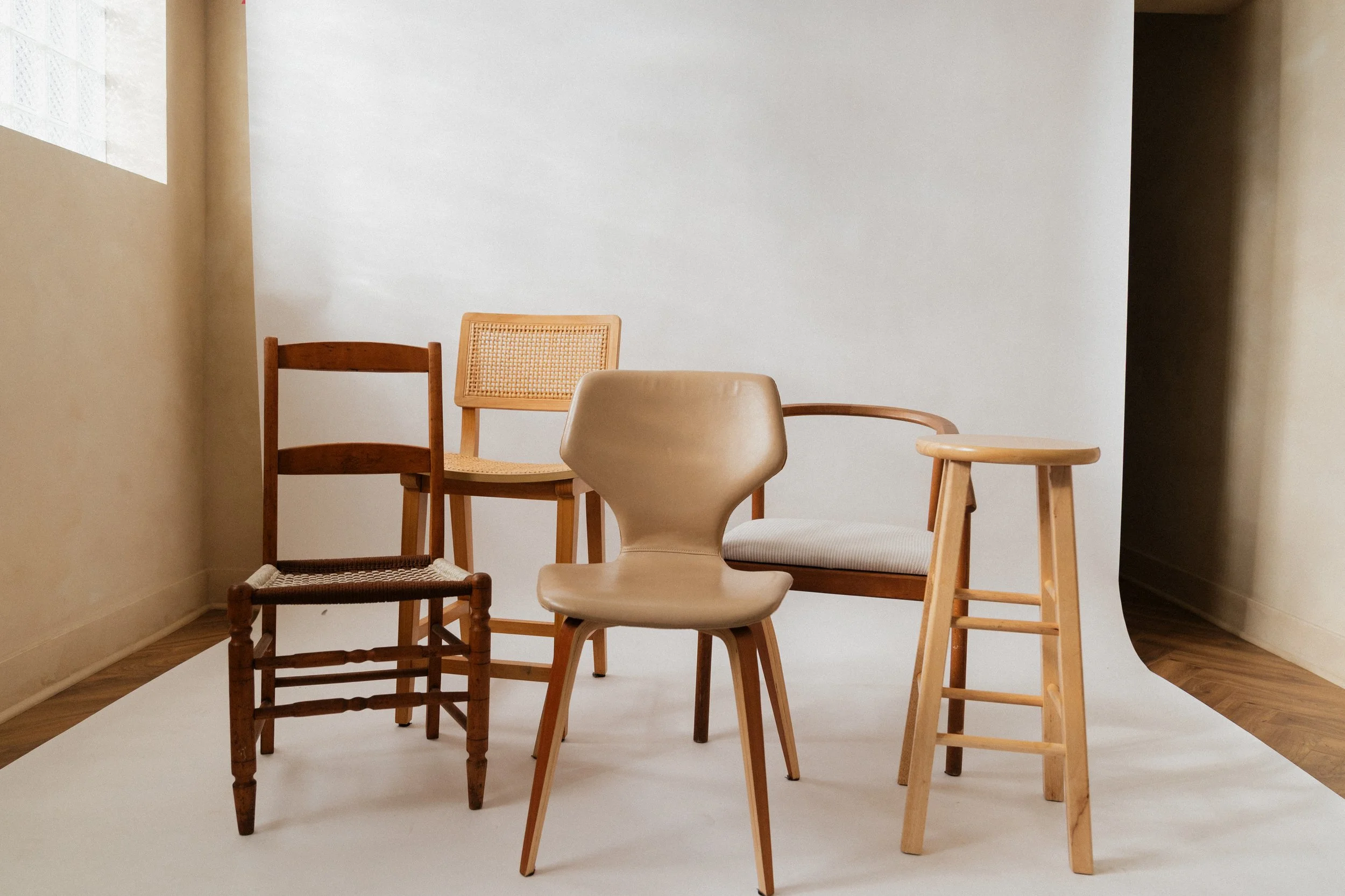 a collection of wooden and leather chairs on a white backdrop with natural lighting Grand Rapids photo studio