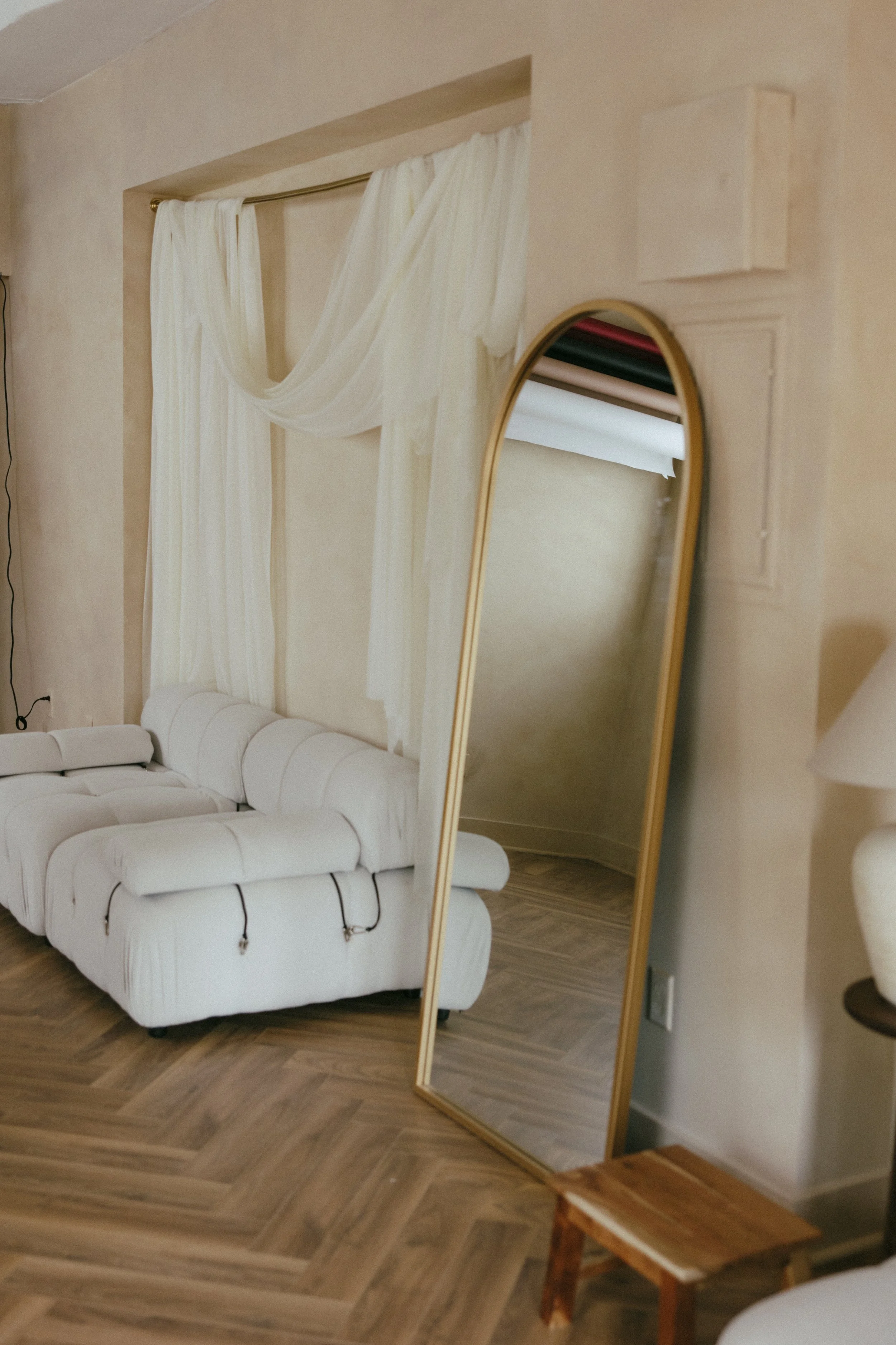 A white sofa with rolled arms and black accents, positioned in a room with light-colored walls and wooden herringbone flooring in a rentable creative photo studio in East Grand Rapids Michigan.