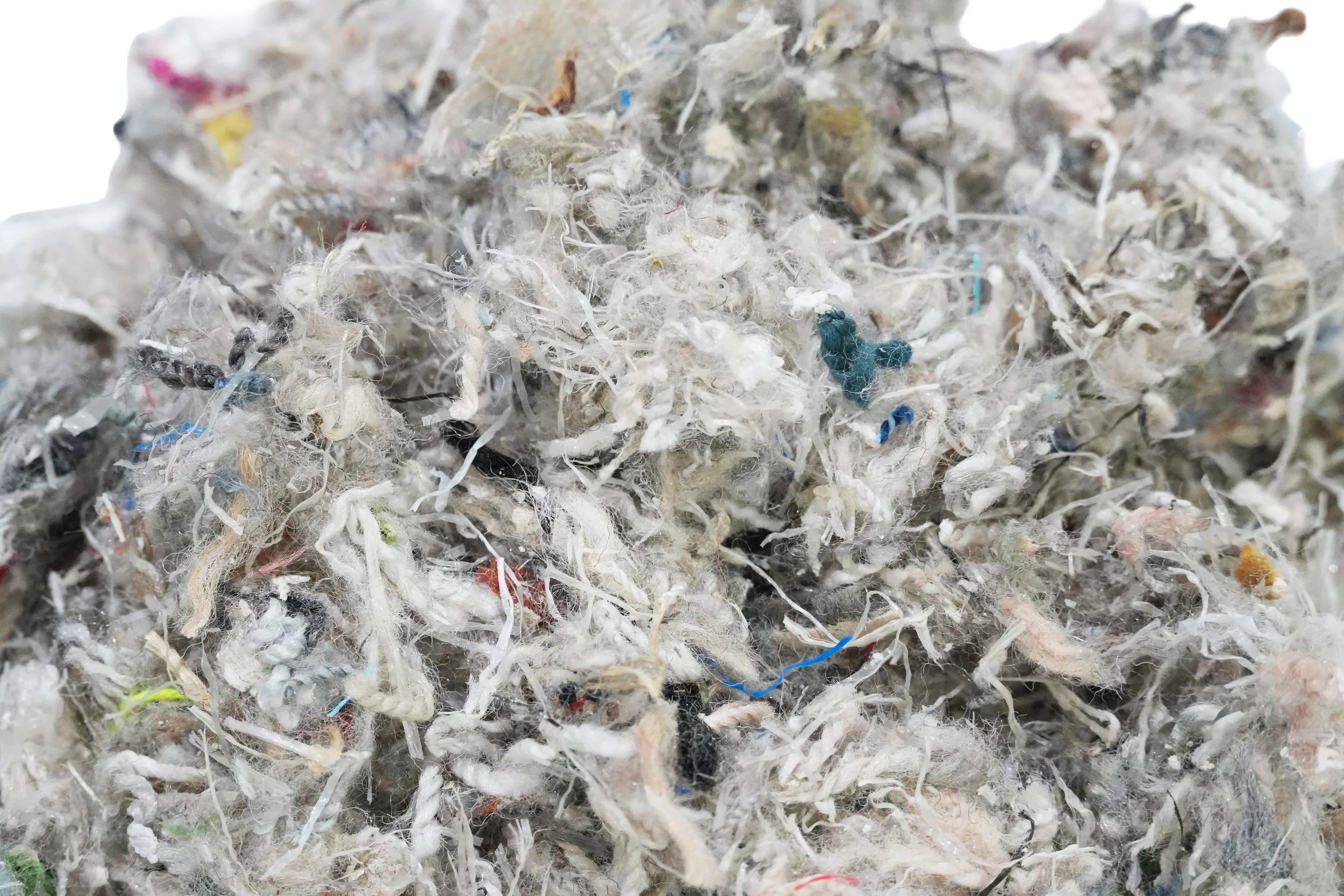 A close-up of a large tangled ball of various colored strings, fibers, and synthetic materials.