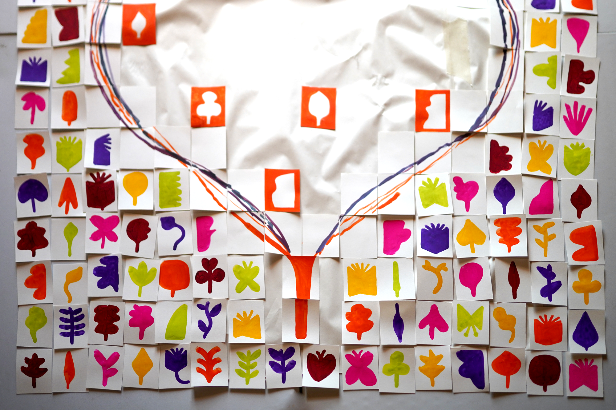 A collage of small white cards, each painted with colorful leaf shapes in pink, purple, orange, yellow, red, and green, arranged on a grid with some crumpled areas and hand-drawn rainbow arcs.