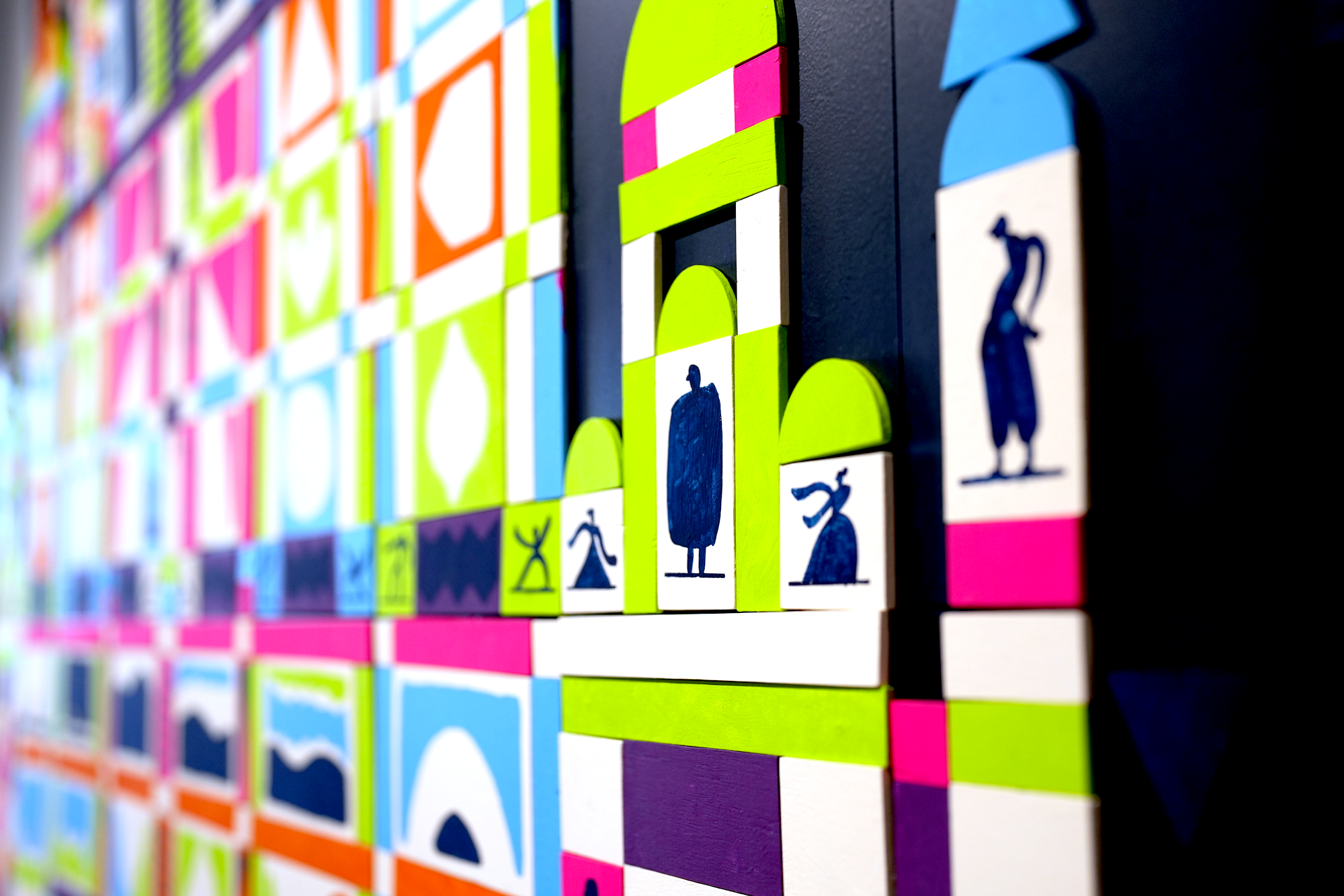 Colorful wooden alphabet blocks arranged on a wall with visible letter houses.