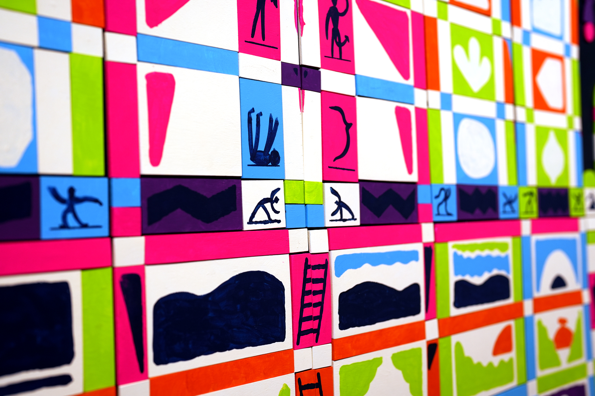 Colorful wall tiles with doodle-style illustrations of people doing yoga and climbing ladders, patterned with pink, white, green, blue, and orange colors.